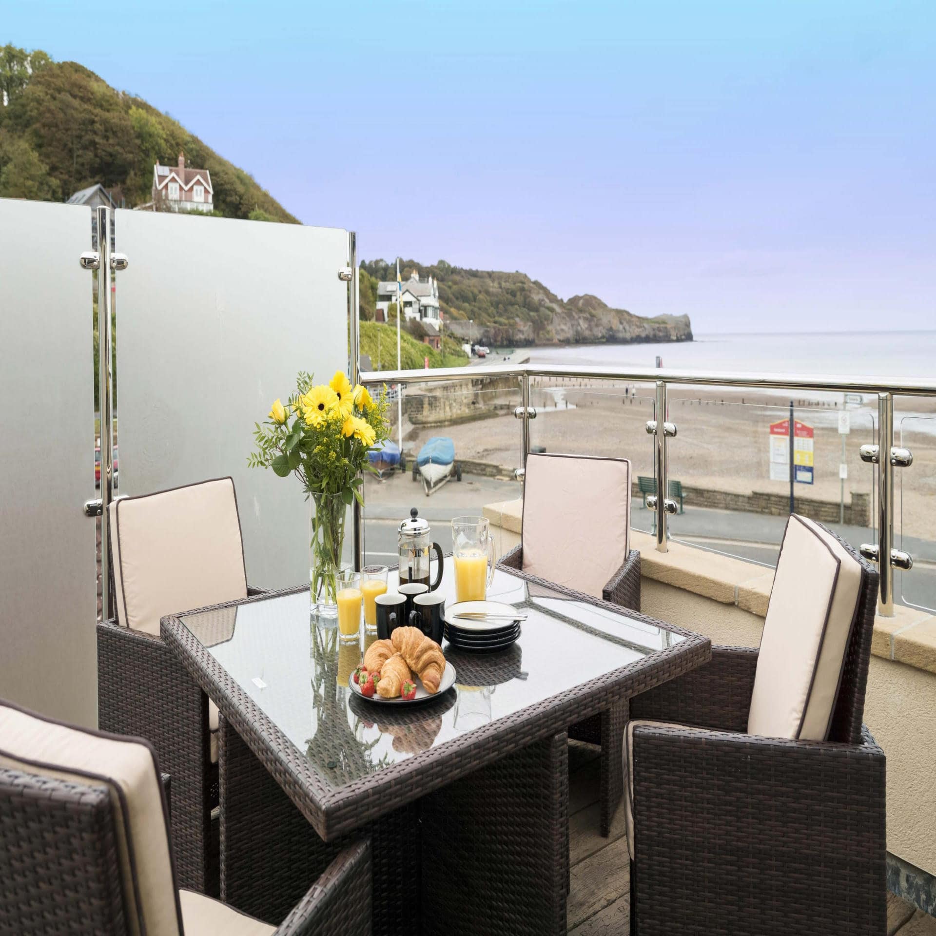 Balkon mit gedecktem Frühstückstisch für 4 Personen und Blick auf den Strand der Nordsee.