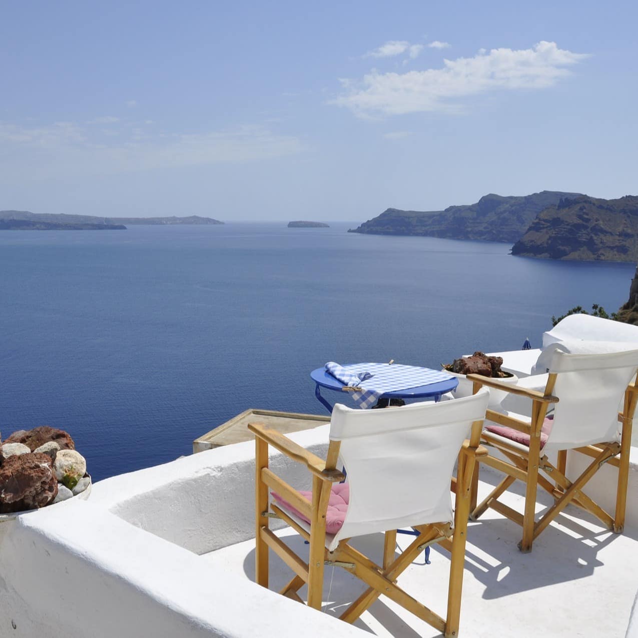 Aussicht auf das Meer und zwei weiße Stühle auf einer Dachterrasse von einem Haus in Griechenland