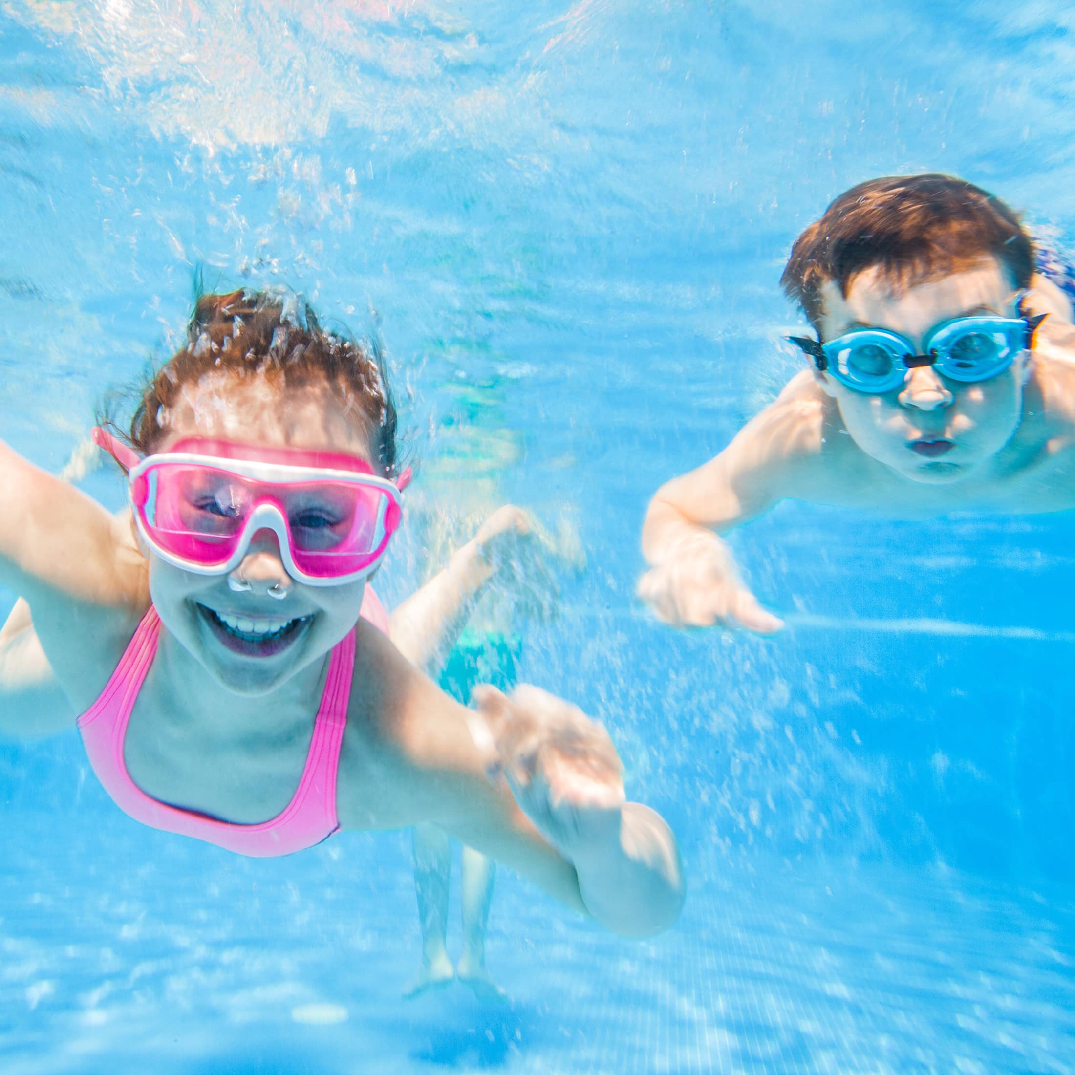 Kinder mit Schwimmbrillen unter Wasser.