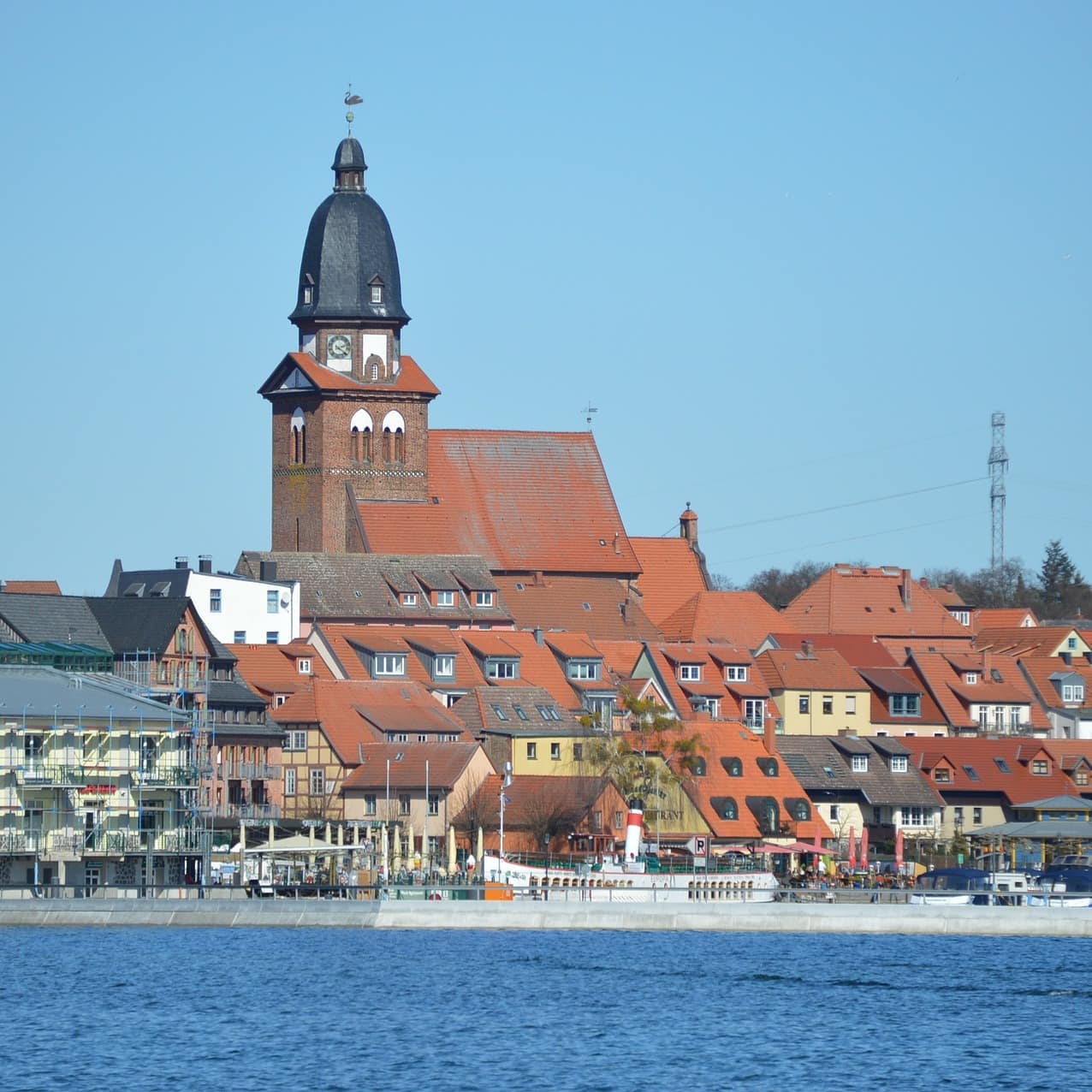 Blick über das Wasser auf die Stadt Waren, zu sehen sind Häuser und eine Kirche