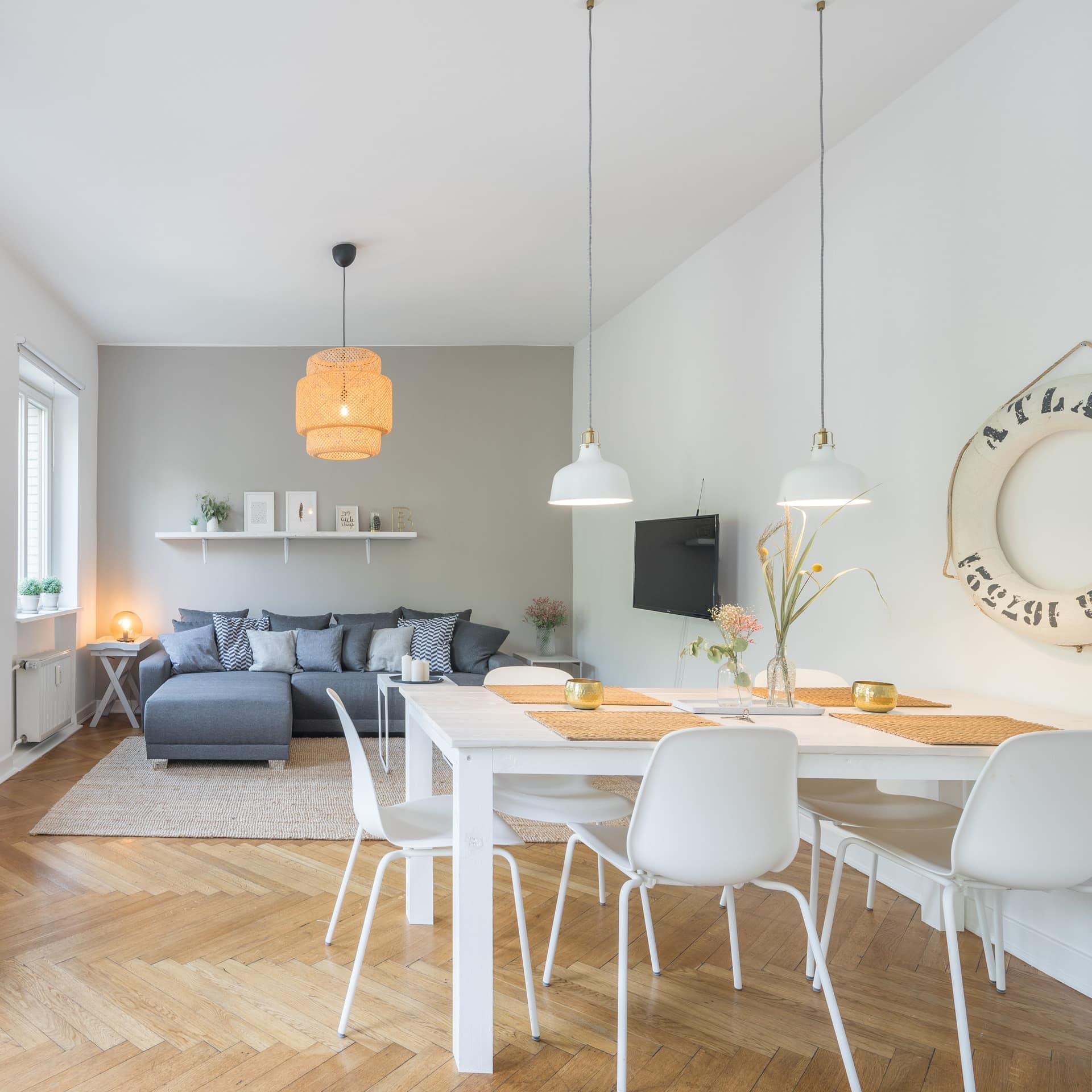 Hell und modern eingerichteter Wohn- und Essbereich einer Wohnung; ein weißer Rettungsring hängt an der Wand.