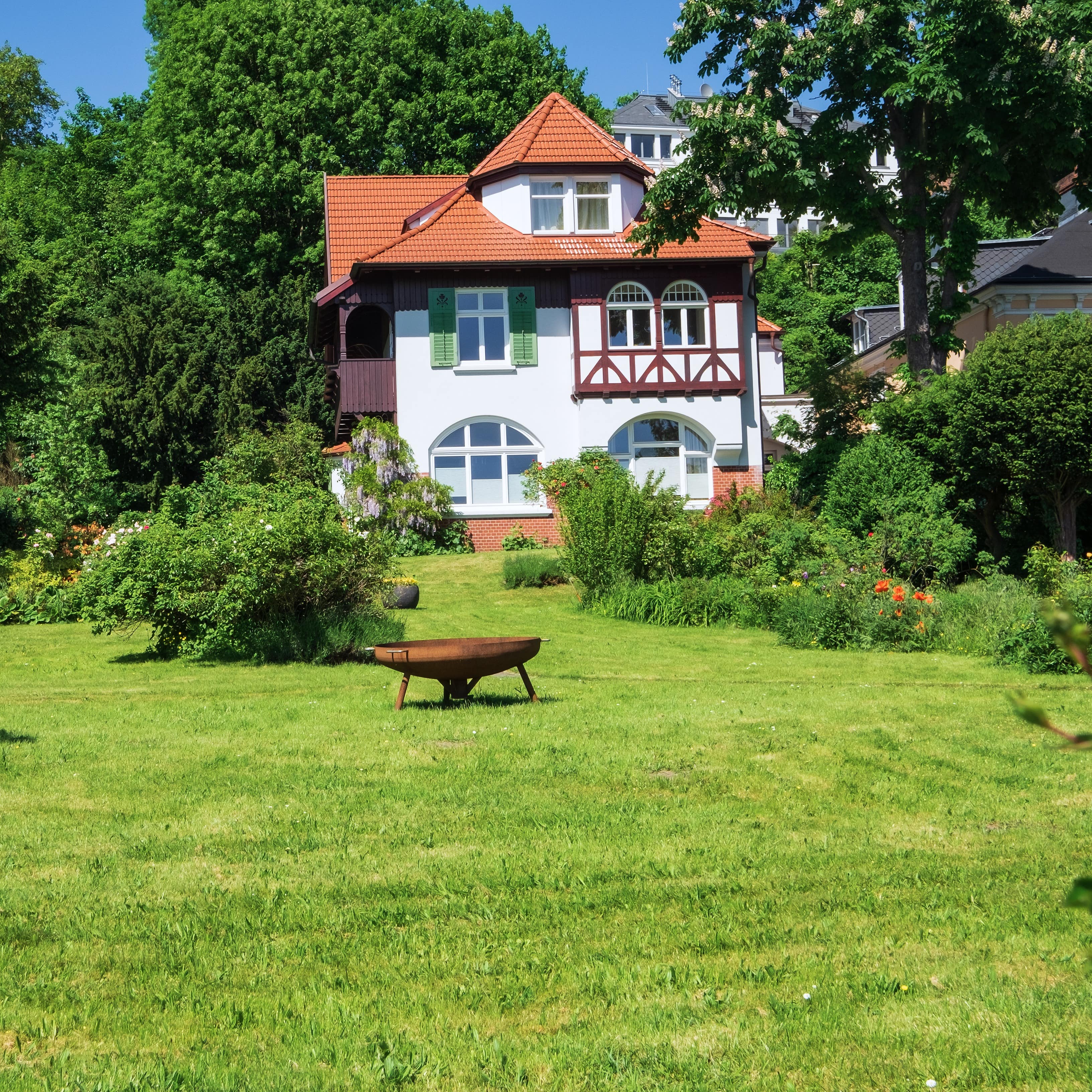 Ein eklektisch wirkendes Haus mit großen, grünen Garten in Hamburg. Die Sonne scheint.