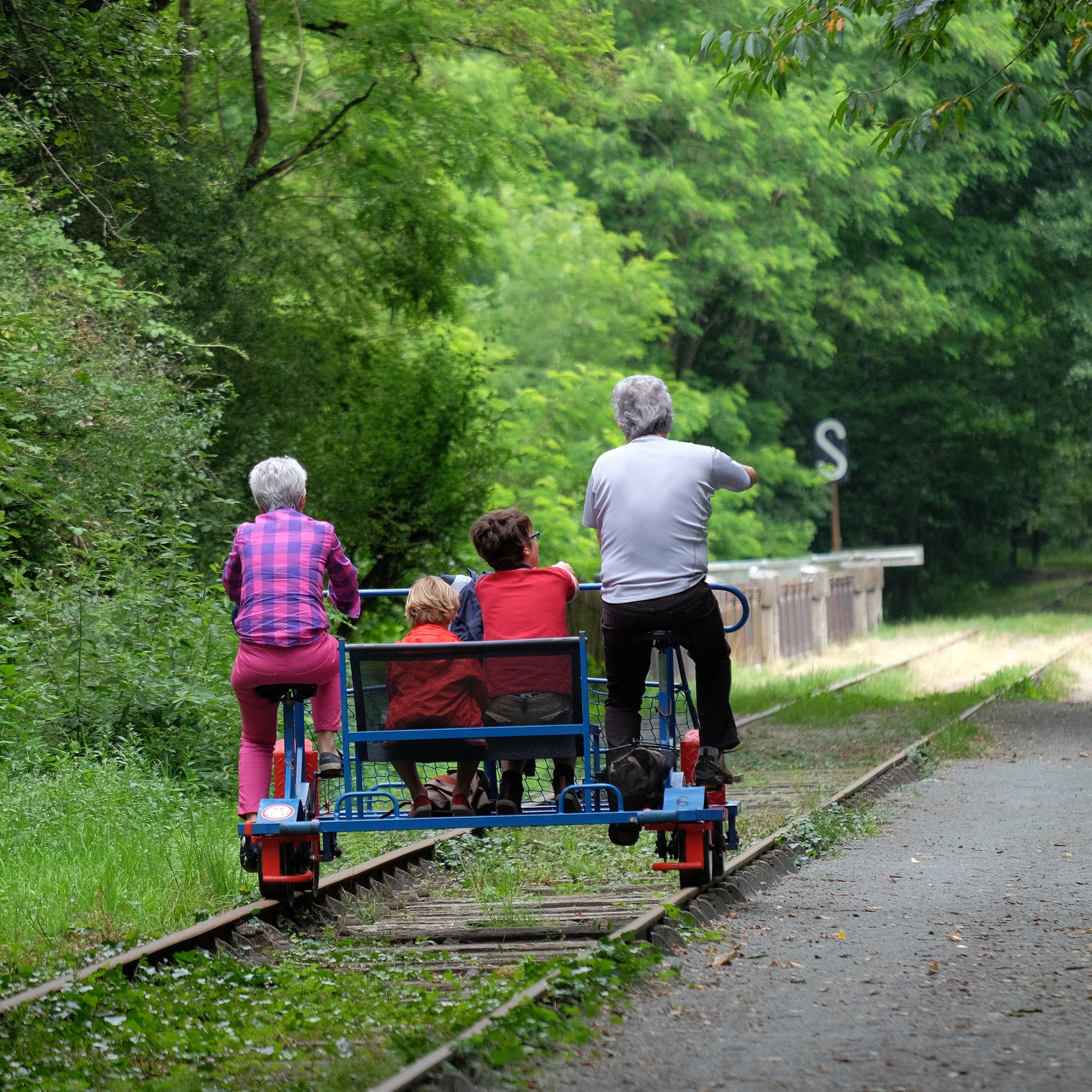 2 Kinder mit Großeltern auf einer Draisine. 