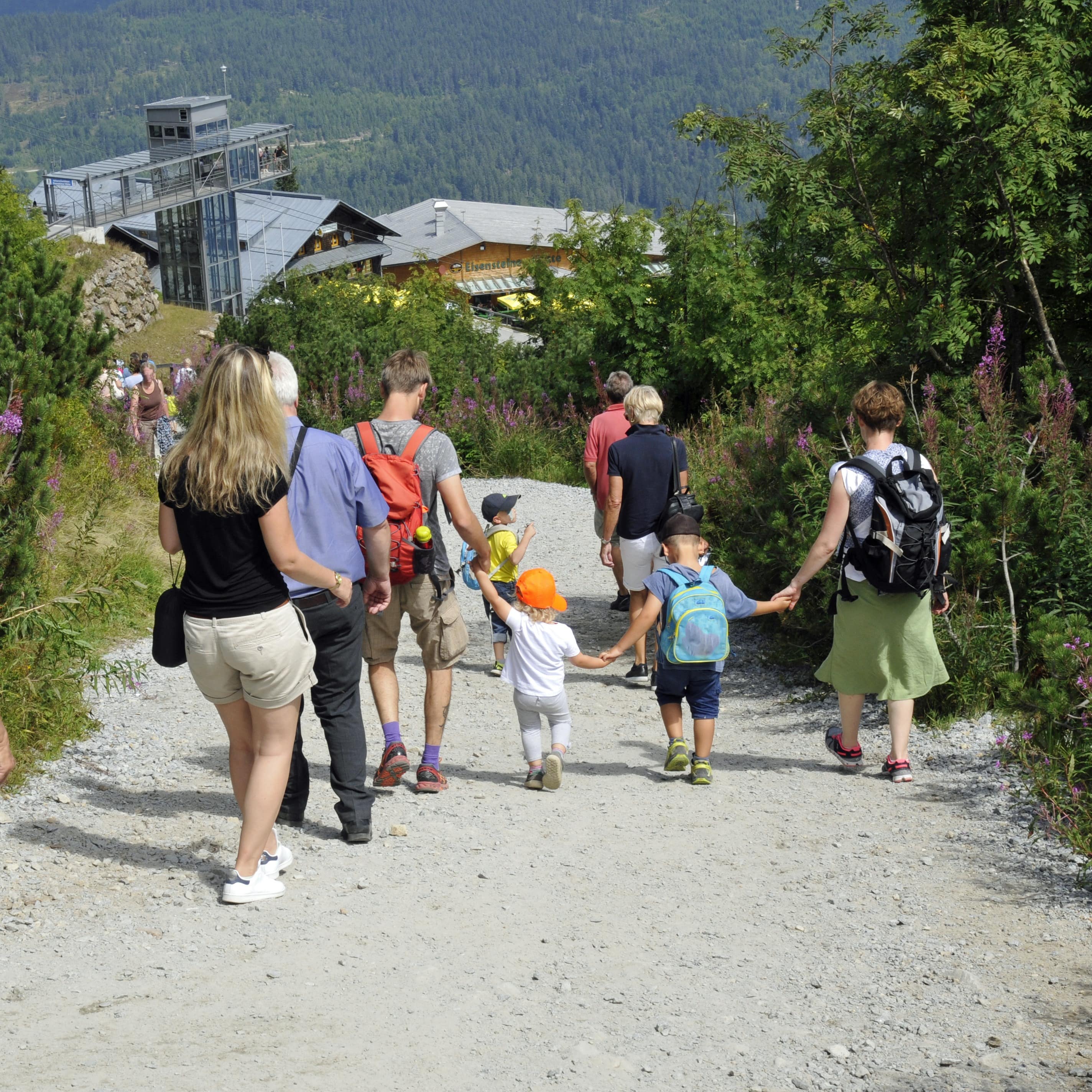 Rückenansicht: Eine Familie mit Kindern und weitere Personen auf einem Wanderweg am Großen Arber.