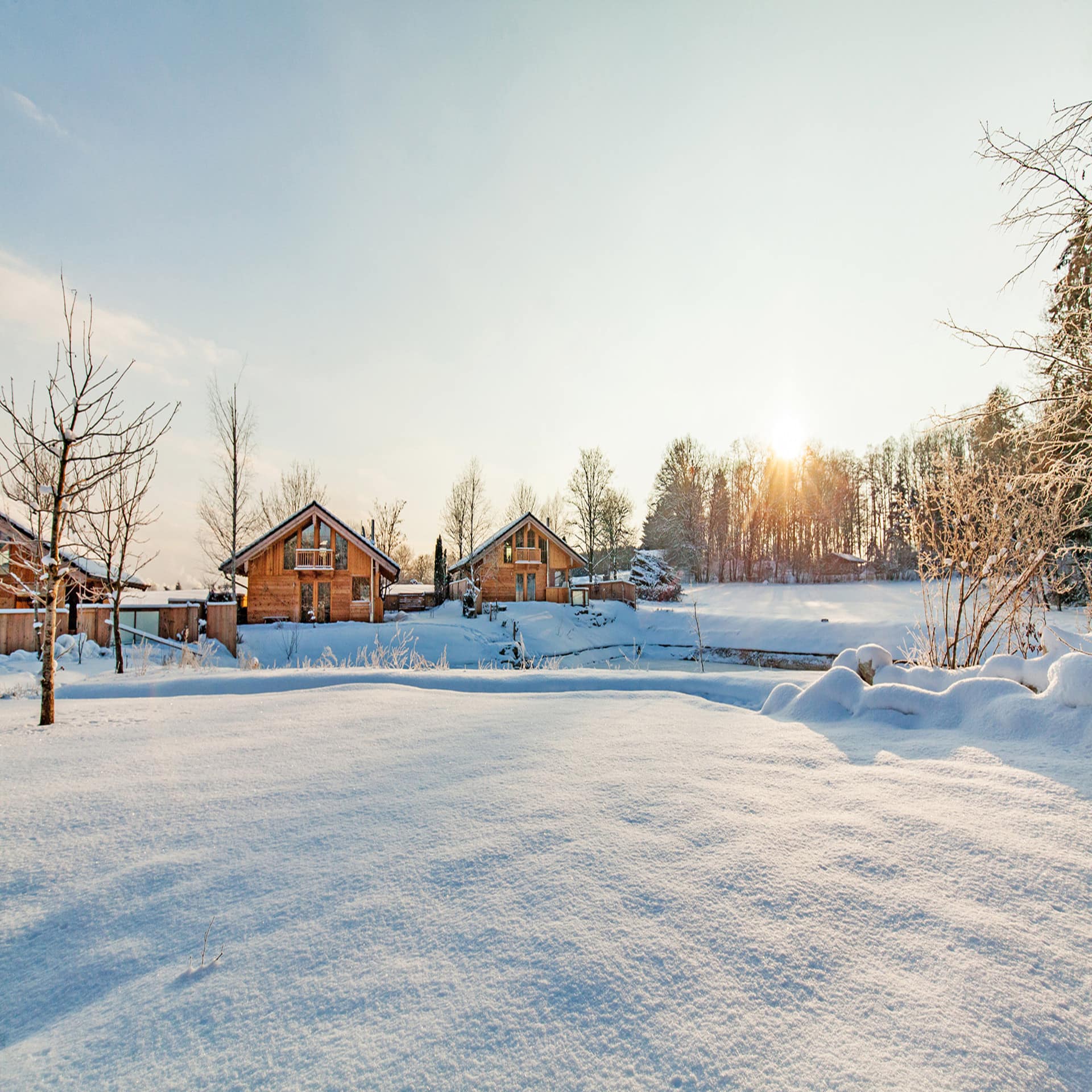 Verschneite Winterlandschaft in der mehrere Holzhäuser stehen.  