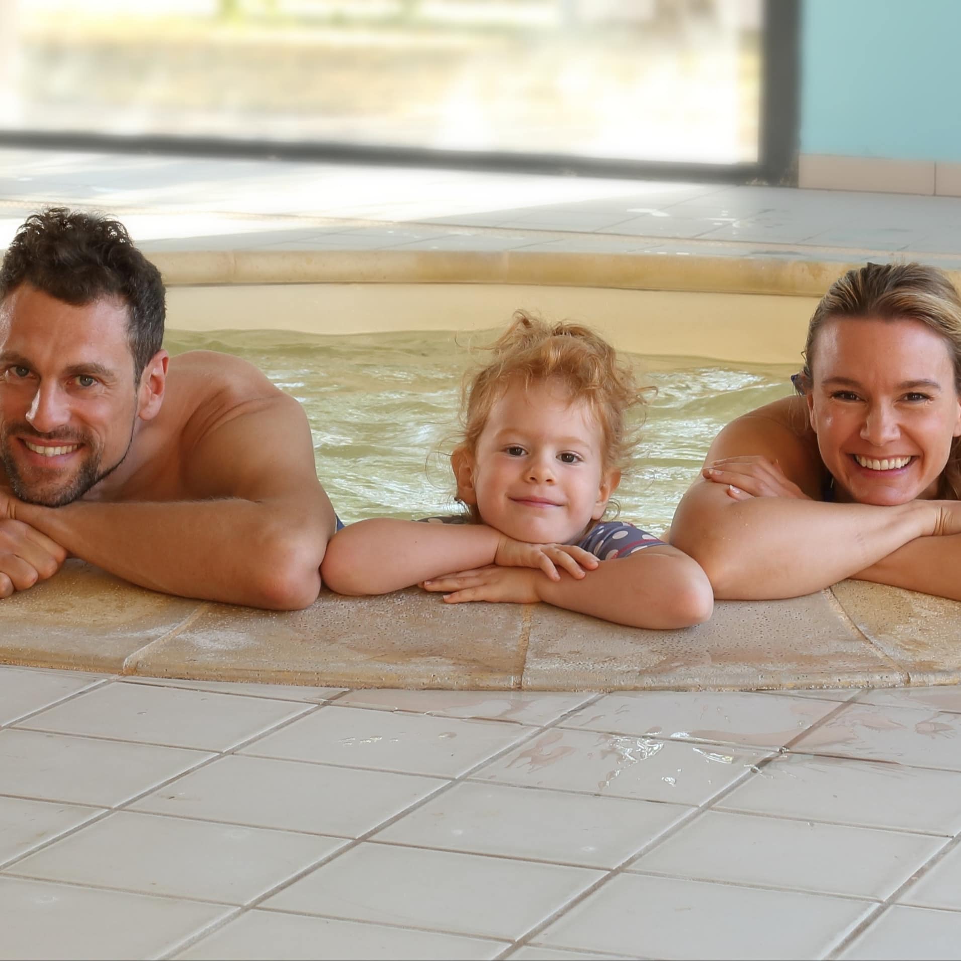 Eltern und Tochter beim Baden im Whirlpool.