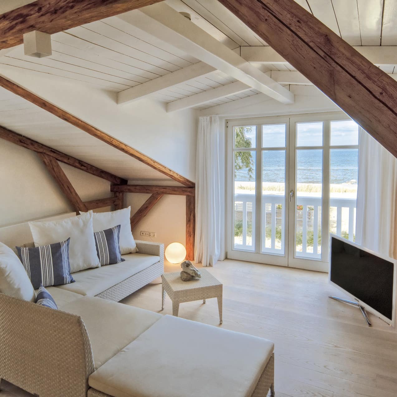 Hell eingerichtetes Wohnzimmer einer Ferienwohnung in Niendorf mit Blick auf das Meer
