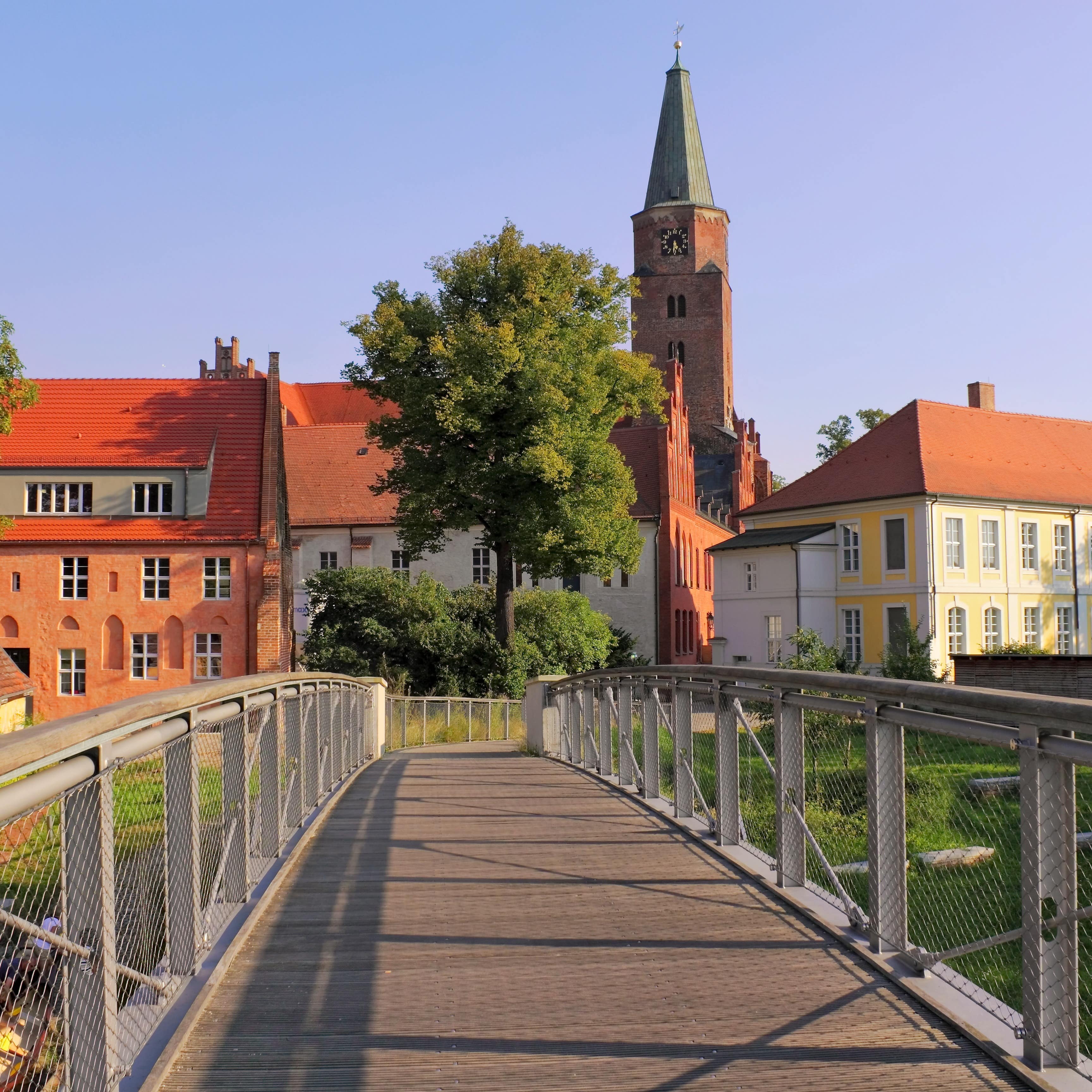 Blick eine Brücke entlang, die zu historischen Gebäuden in Brandenburg an der Havel führt.