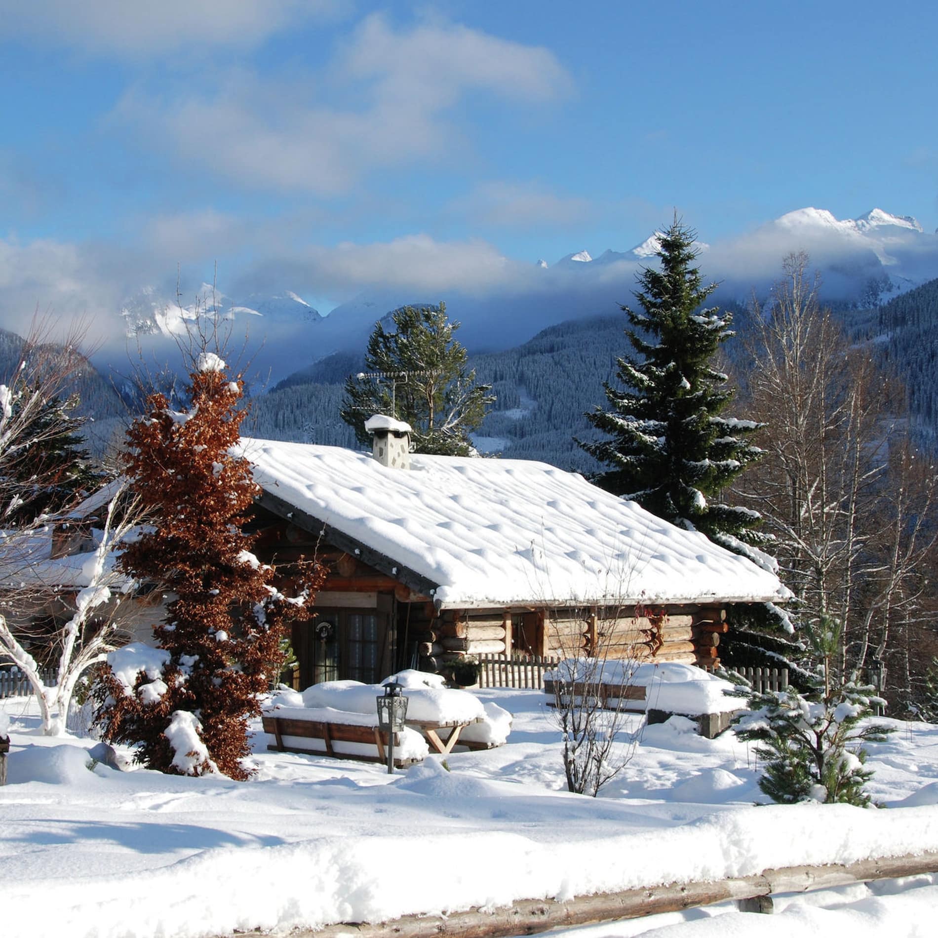 Blockhaus im Winter mit schneebedecktem Haus und Blick auf die Dolomiten 