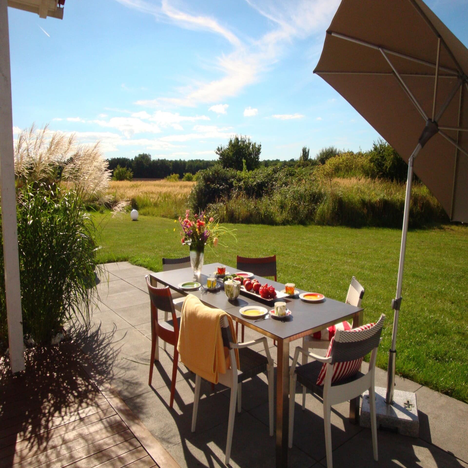 Terrasse mit gedecktem Frühstückstisch und Blick auf die Natur. 
