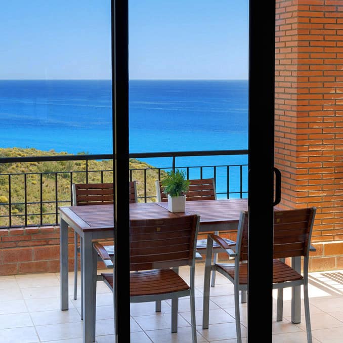 Ferienwohnung in Spanien an der Costa del Sol mit großem Balkon, darauf Tisch und Stühle, und Blick über das azurblaue Meer