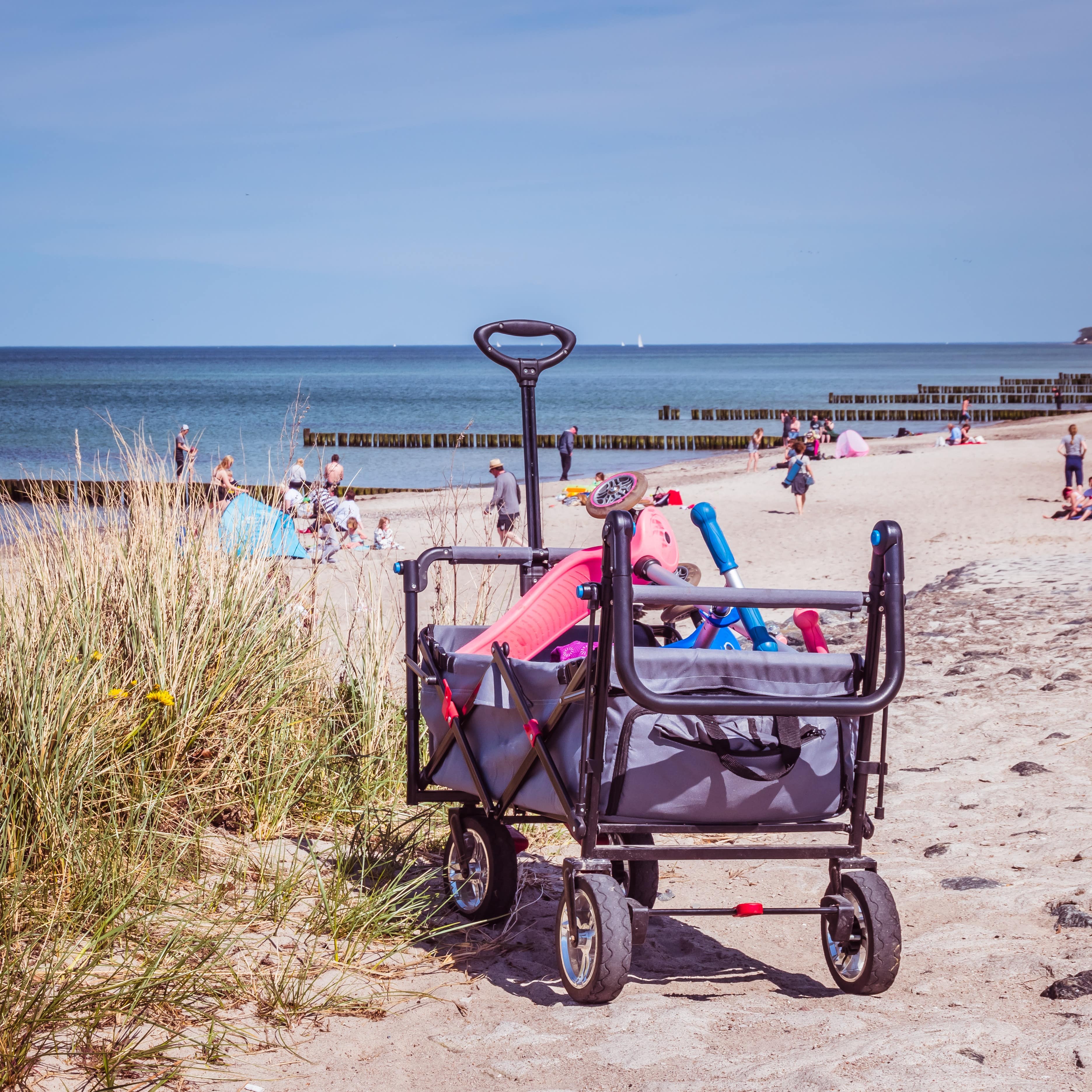 Bollerwagen mit Kinderspielzeug am Strand von Warnemünde.