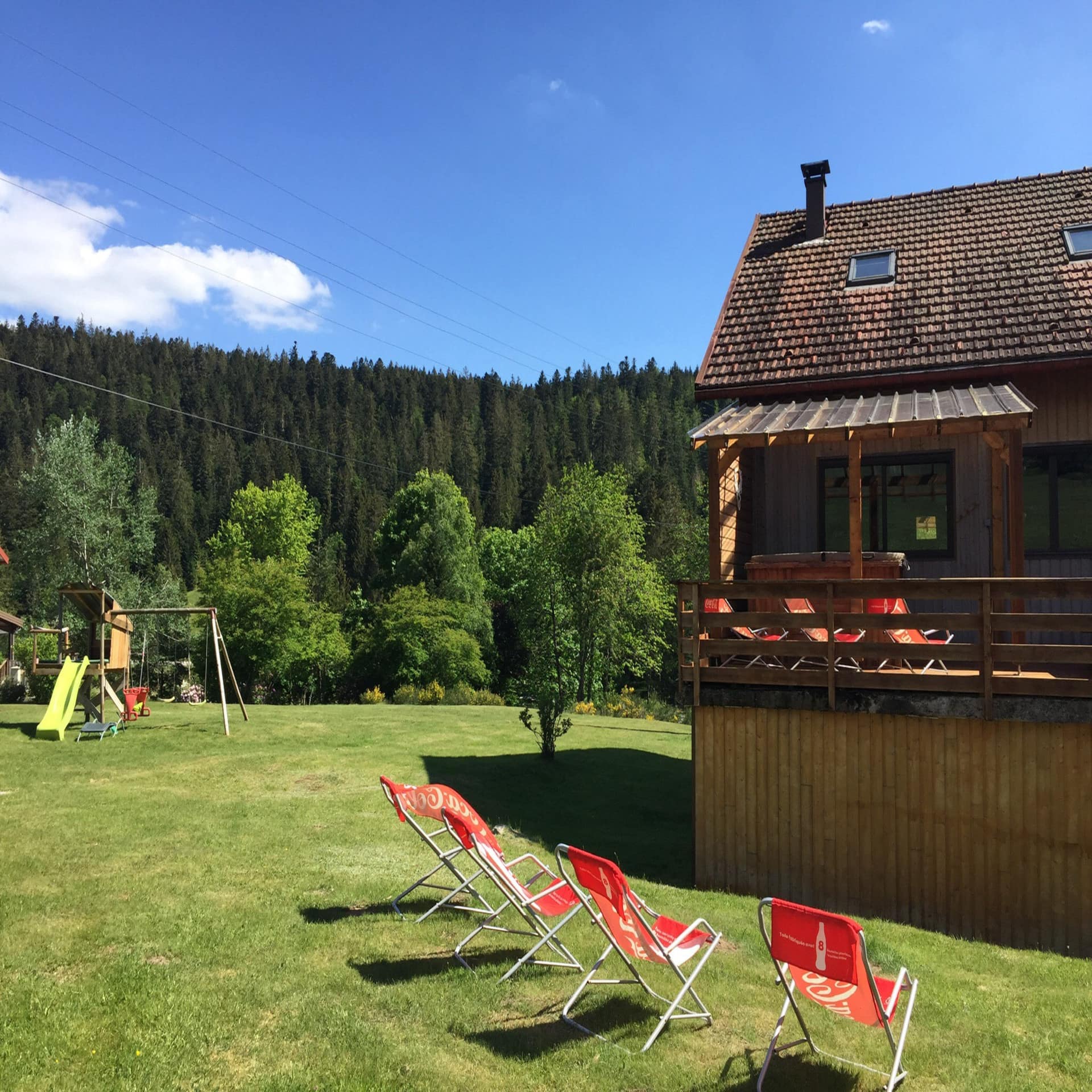 Bauernhaus mit großen Garten, Sonnenstühlen und Spielplatz im Sommer.