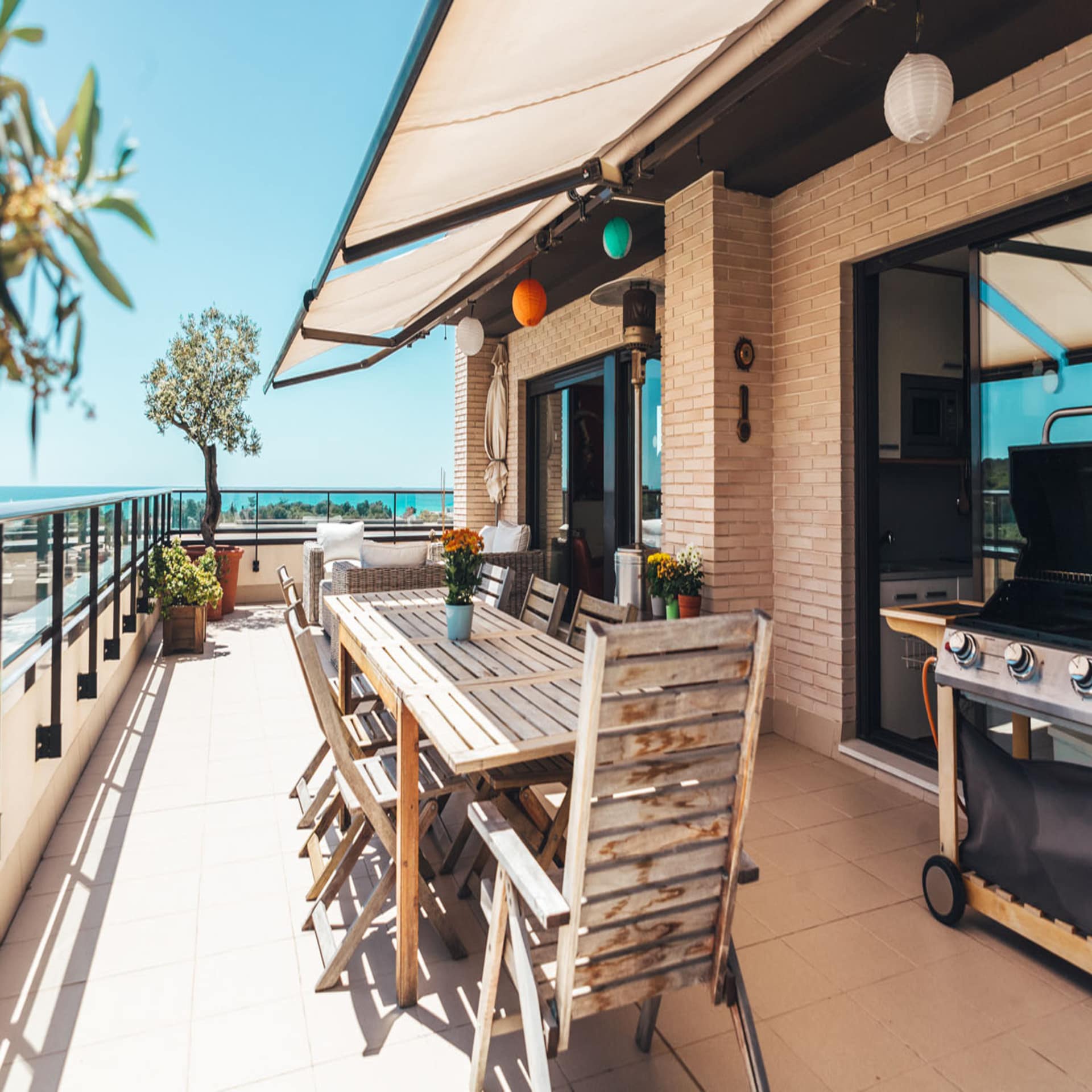 Großer, sonniger Balkon mit Esstisch, Grill und Meerblick.