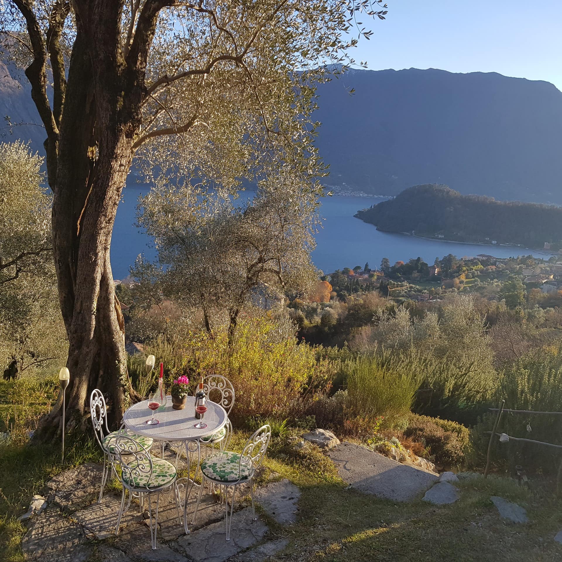 Eine kleine Terrasse mit Tisch und Stühlen einer Ferienwohnung am Comer See mit Blick auf den See