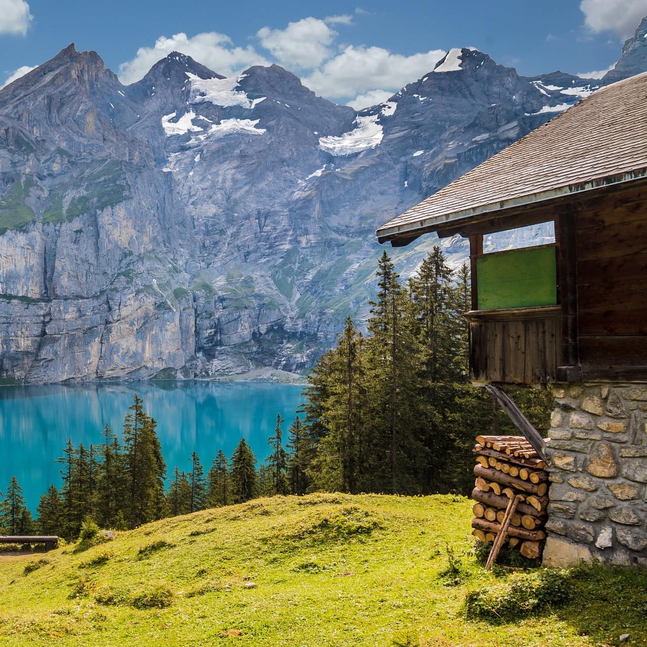 Eine Hütte auf einer Wiese an einem Bergsee im Sommer.