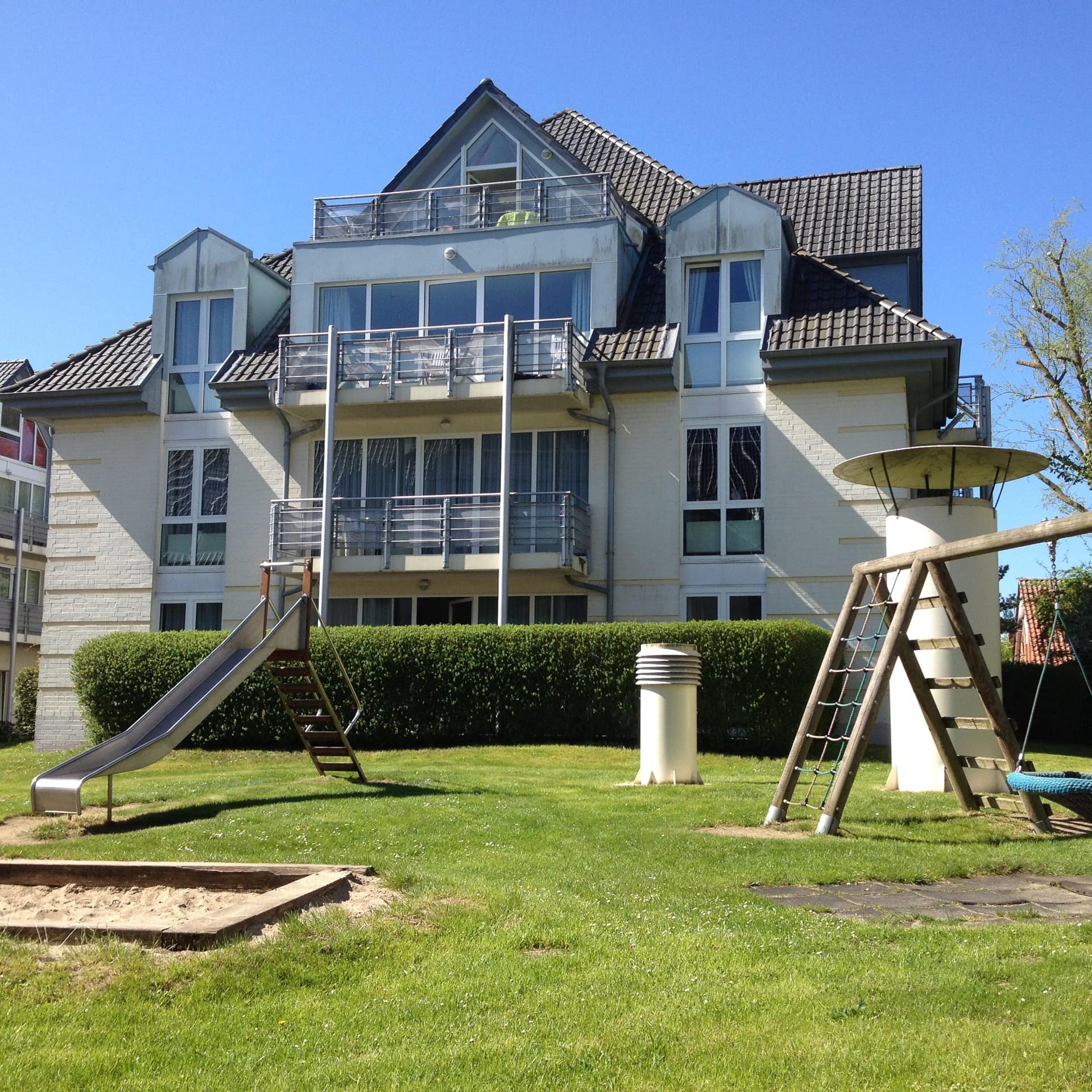 Blick über einen Spielplatz auf ein Haus mit Ferienwohnungen in Boltenhagen