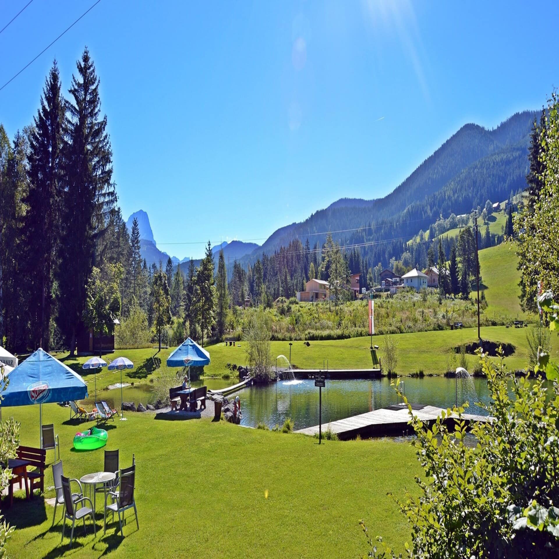 Ein Waldbad mit großer Liegewiese, Sitzgelegenheiten und Sonnenschirmen.