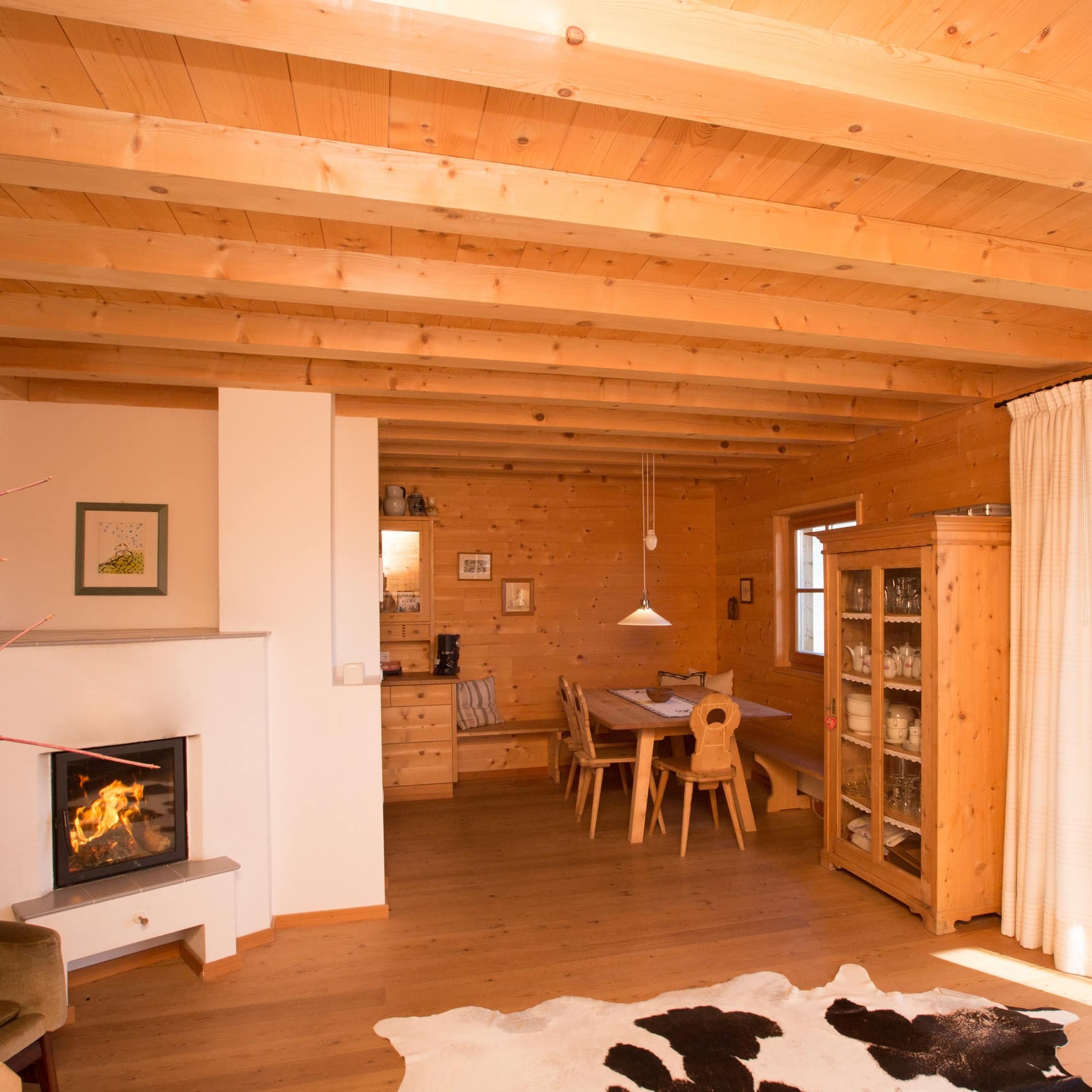 Ein Kaminfeuer brennt im Wohnzimmer der Ferienwohnung in Marling, in der helles Holz vorherrscht 