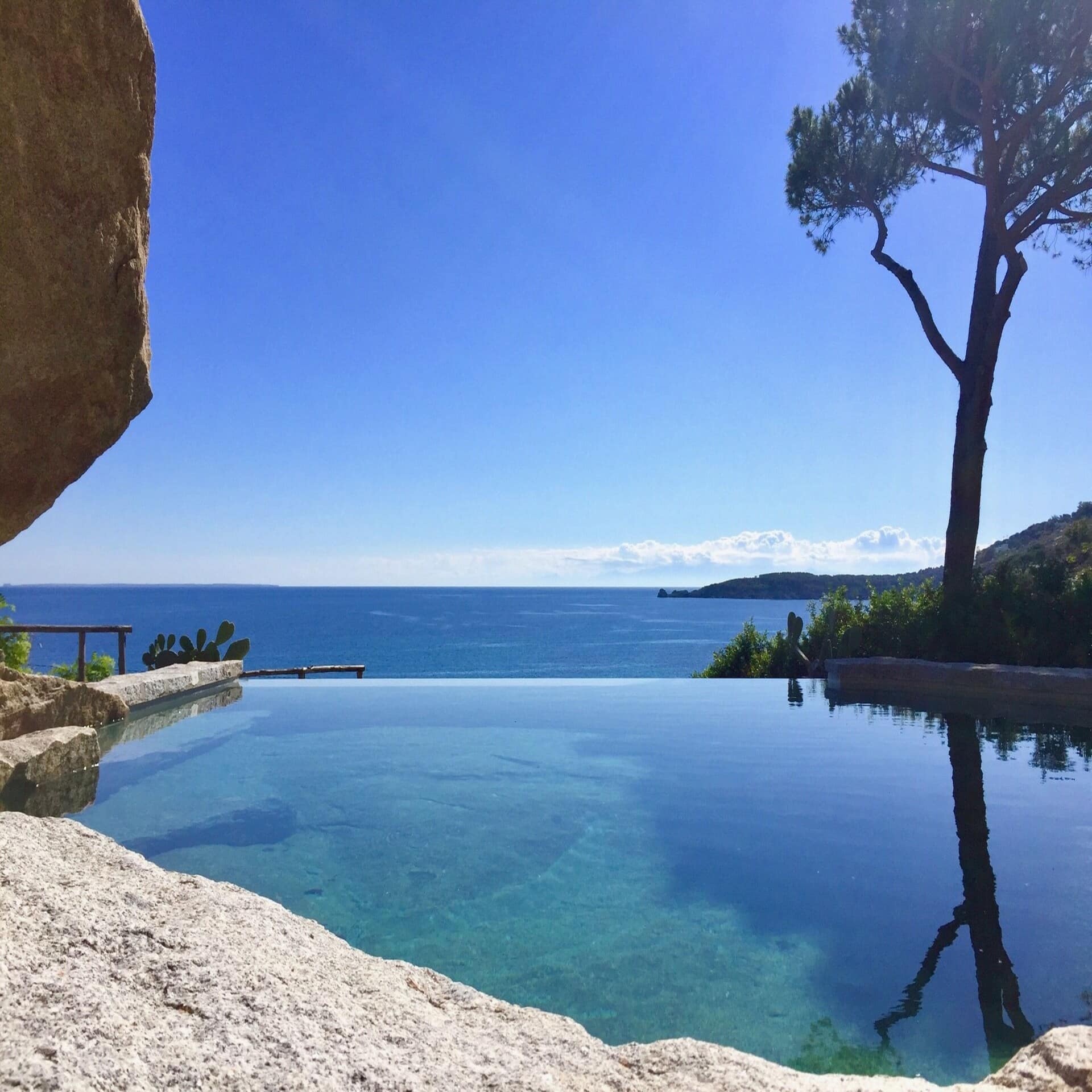 Infinity Pool in einem Garten mit Panoramabick auf das Meer.