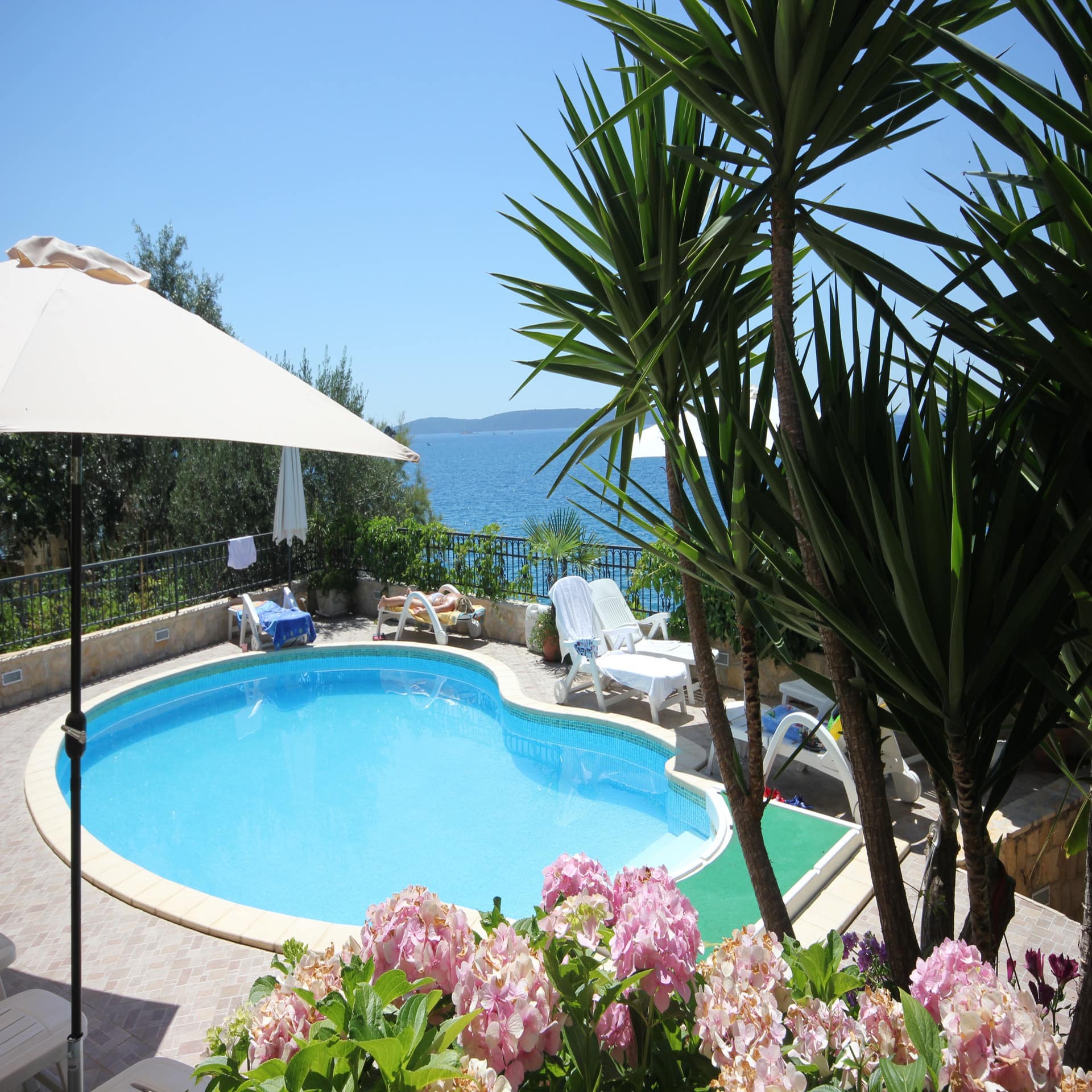 Terrasse mit Pool und Sonnenliegen und Blick auf das Meer.