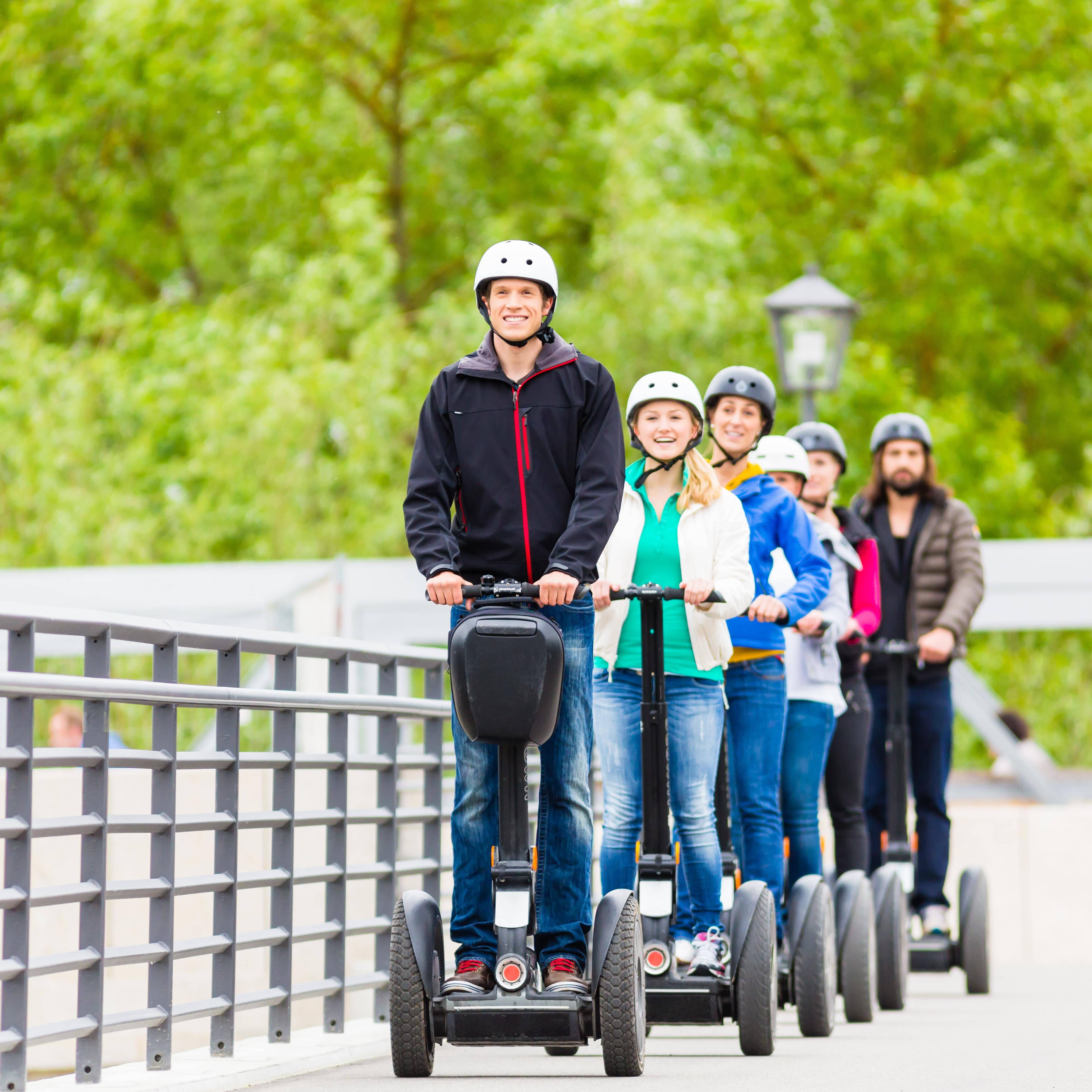 Junge Touristen bei einer Segway Tour, alle haben Helme auf.