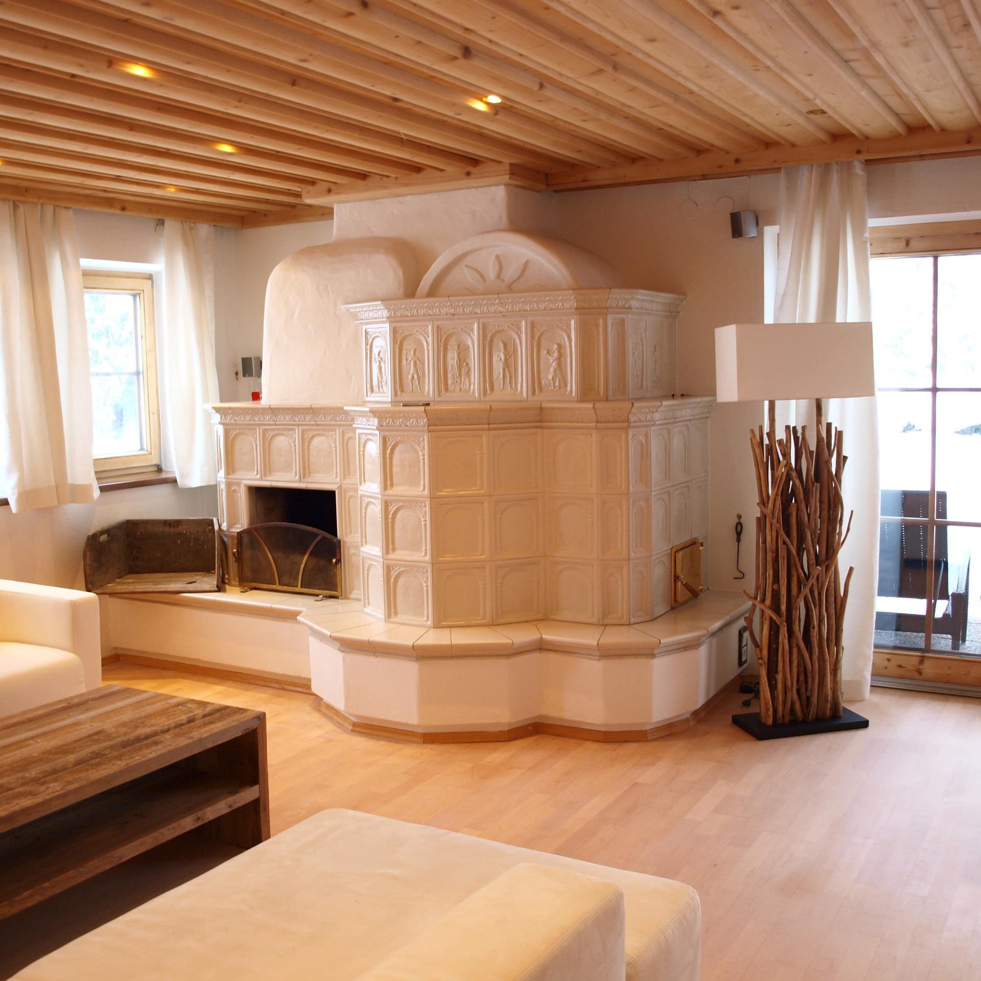 Stube mit Kachelofen und modernen Möbeln in einem Luxus-Chalet bei St. Johann in Tirol
