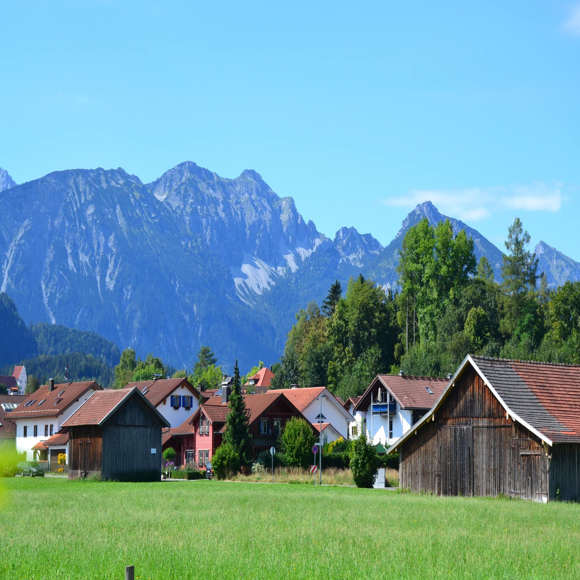 Blick von einer Wieser auf Füssen im Allgäu. Die Sonne scheint.