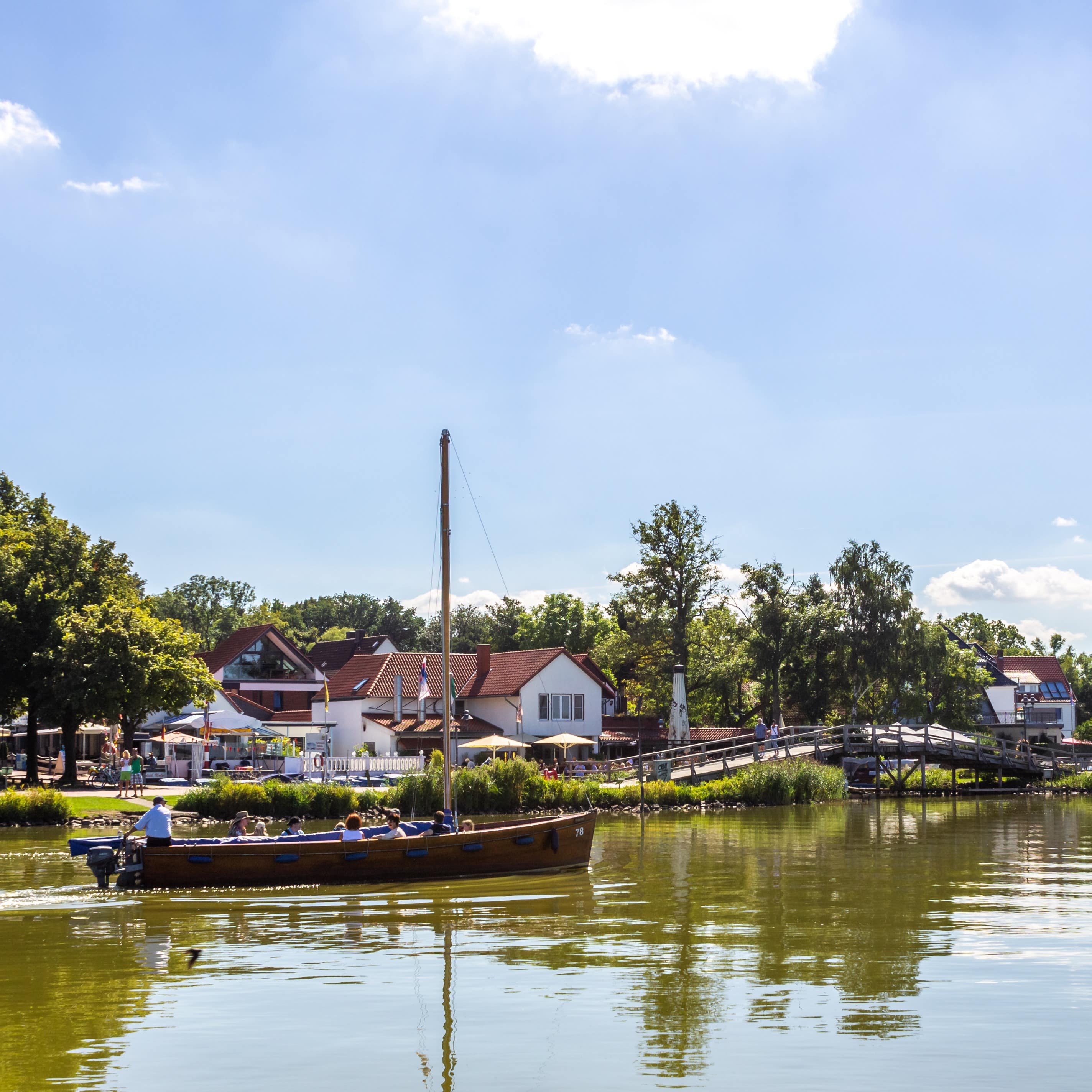 Blick über das Wasser auf Steinhude, im Wasser ein Ausflugsboot.