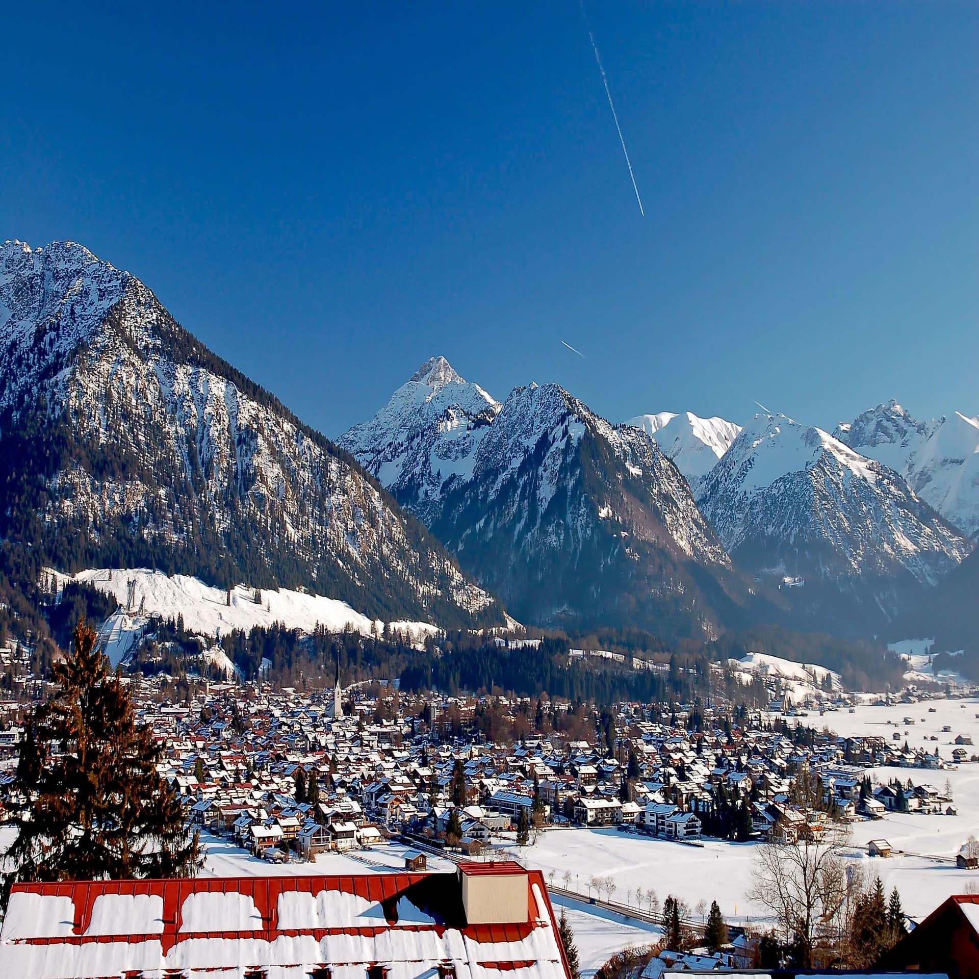 Blick auf das verschneite Oberstdorf und die Berge im Hintergrund.