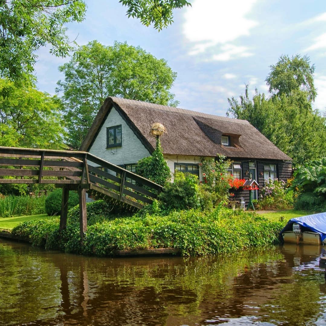 Blick auf ein Haus an einem Kanal, das über eine Brücke zu erreichen ist