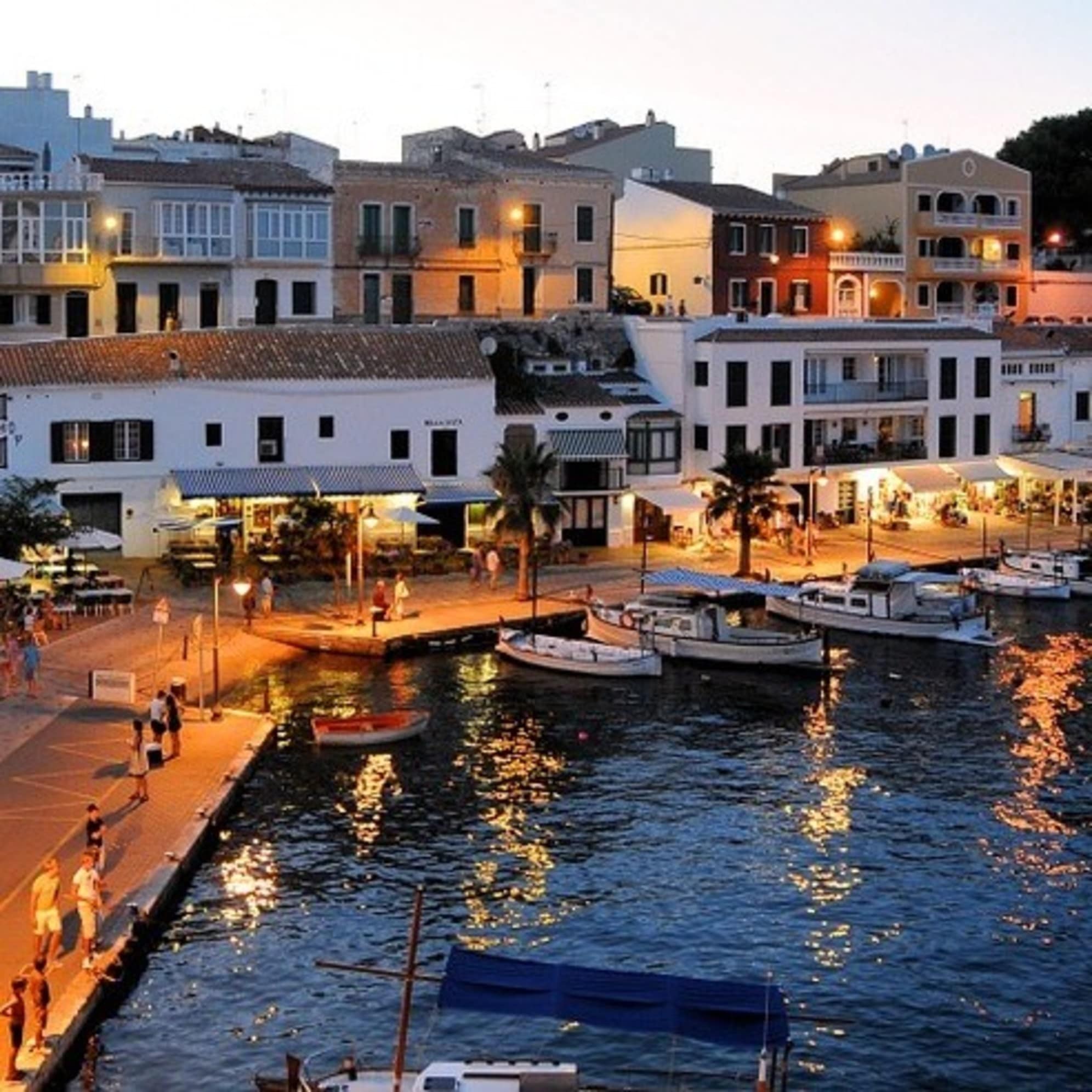 Hell erleuchtete Hafenpromenade von Menorca bei Sonnenuntergang
