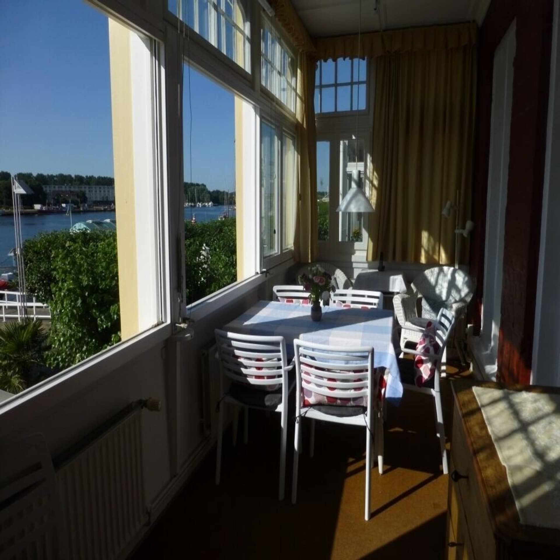 Eine Veranda mit Tisch und Stühlen und Blick auf das Wasser. 