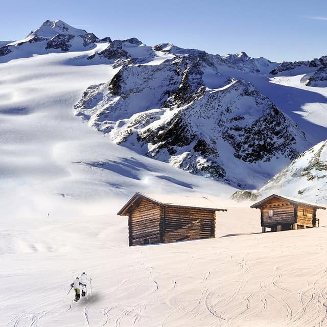 Zwei kleine Hütten inmitten einer alpinen Winterlandschaft