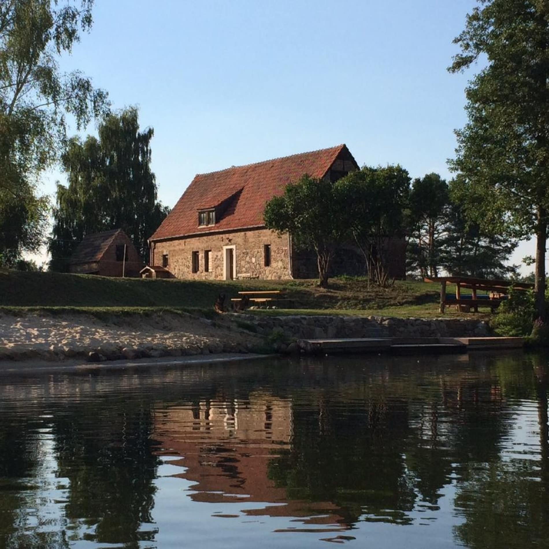 Blick vom Wasser auf einen Steinbungalow am Schwielochsee direkt am Wasser mit großen Garten