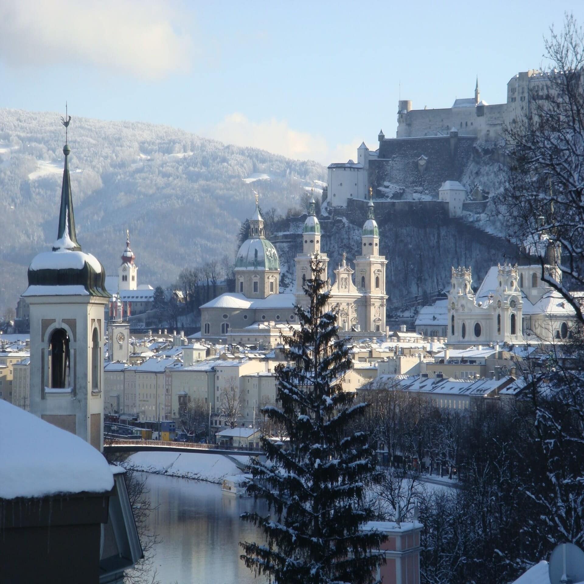 Blick aus einem Fenster auf die verschneite Altstadt von Salzburg.