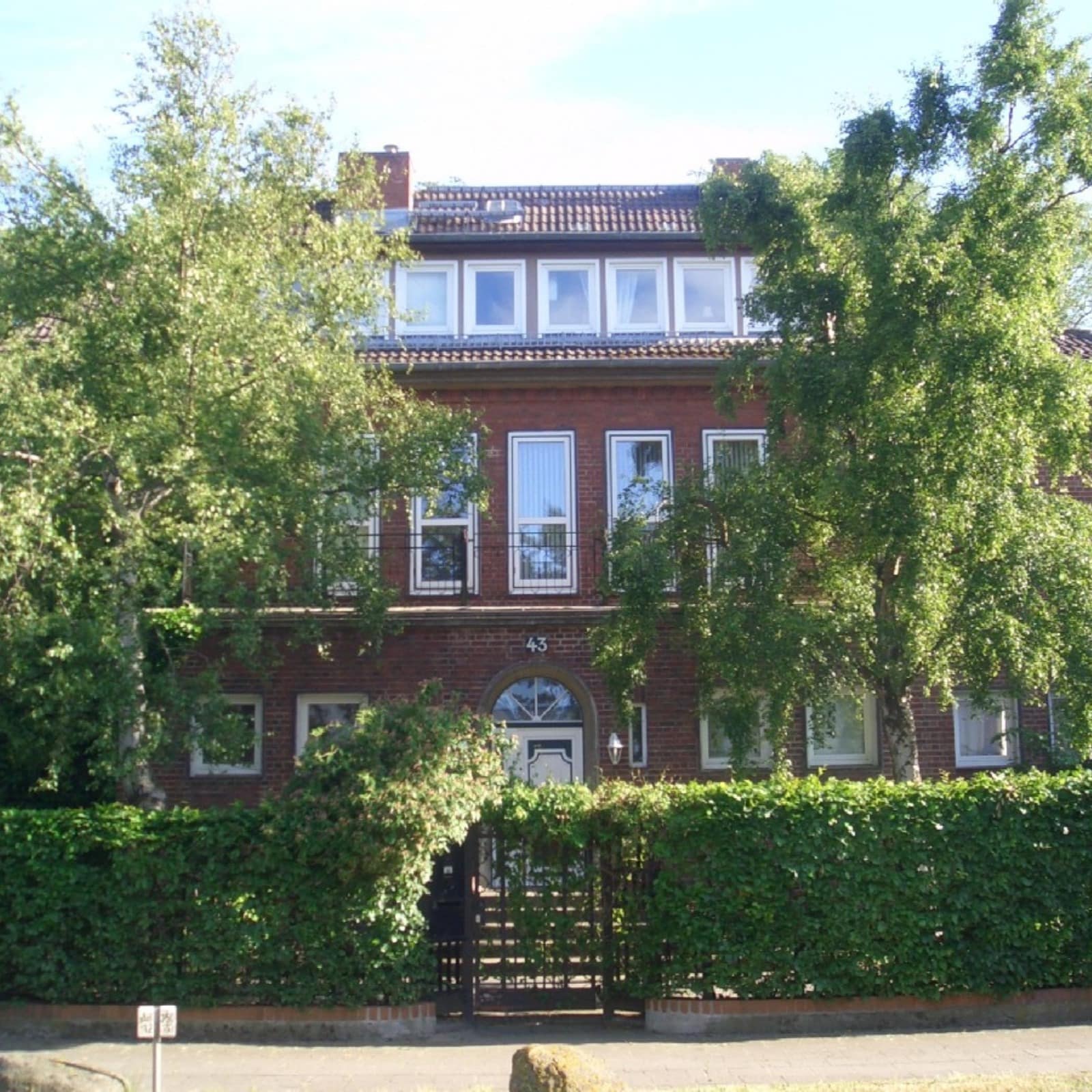 Haus mit Hecke und Bäumen, in dem sich Ferienwohnungen in Warnemünde befinden