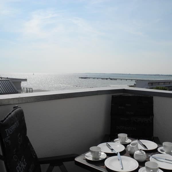 Blick vom Balkon auf die Ostsee, der Tisch der Ferienwohnung in Großbrode ist gedeckt.