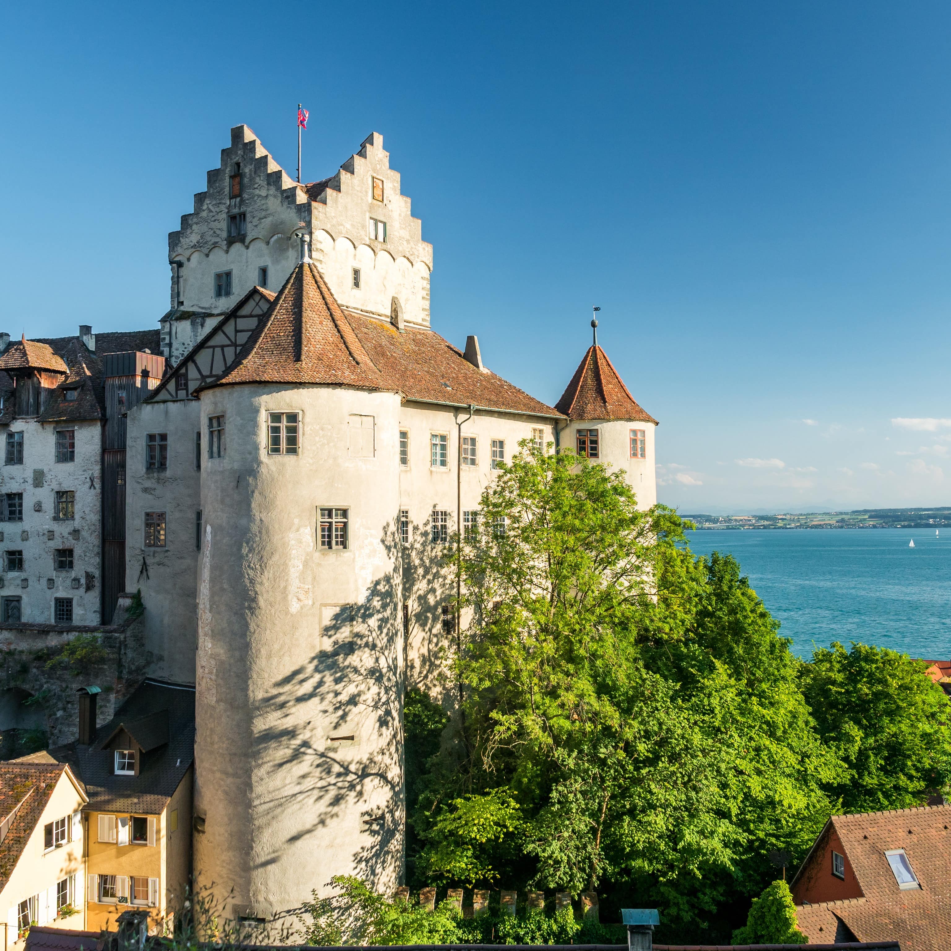 Blick auf die Burg in Meersburg, die umliegenden Häuser und den Bodensee im Hintergrund.