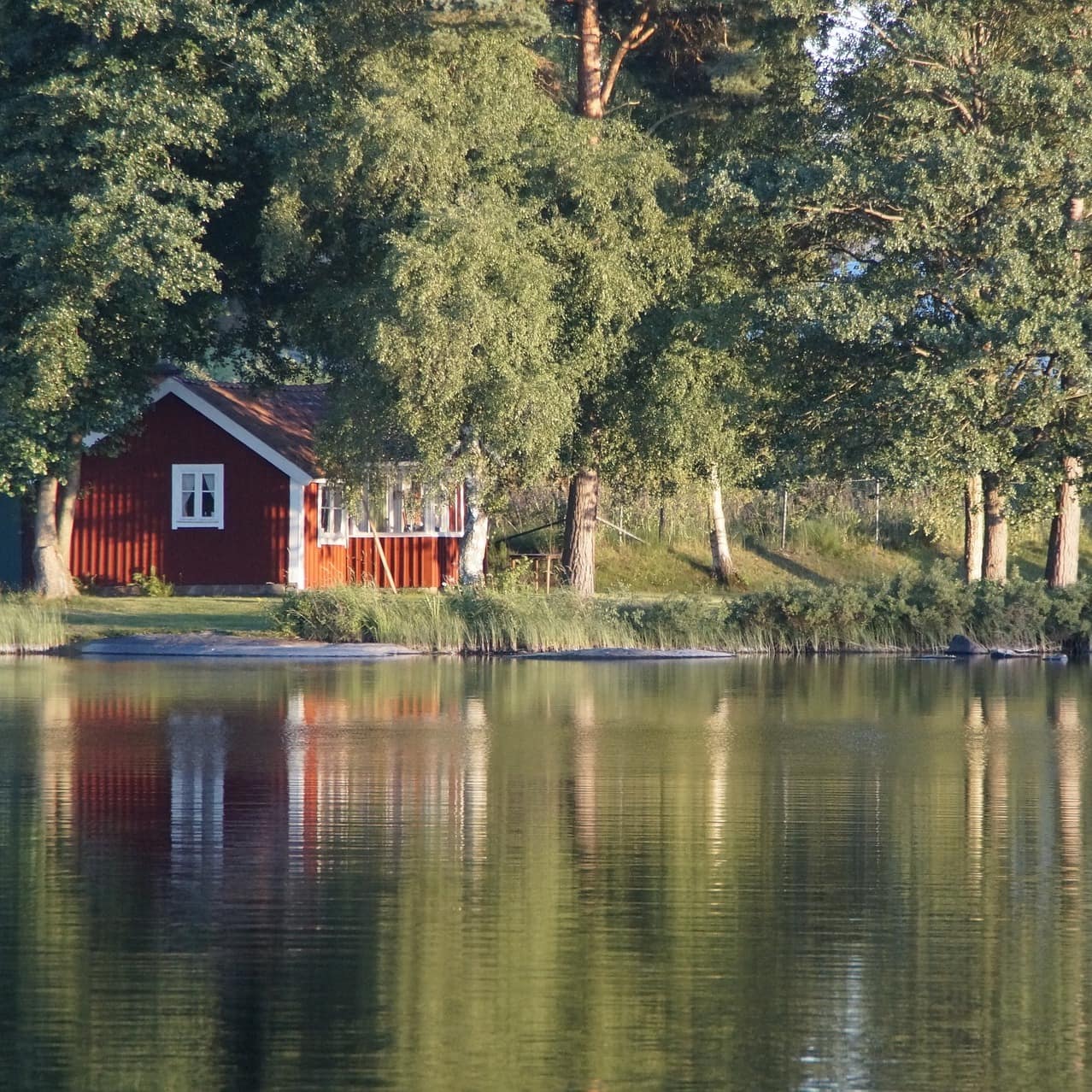 Ein idyllisch gelegenes rot-weißes Ferienhaus in Schweden am See