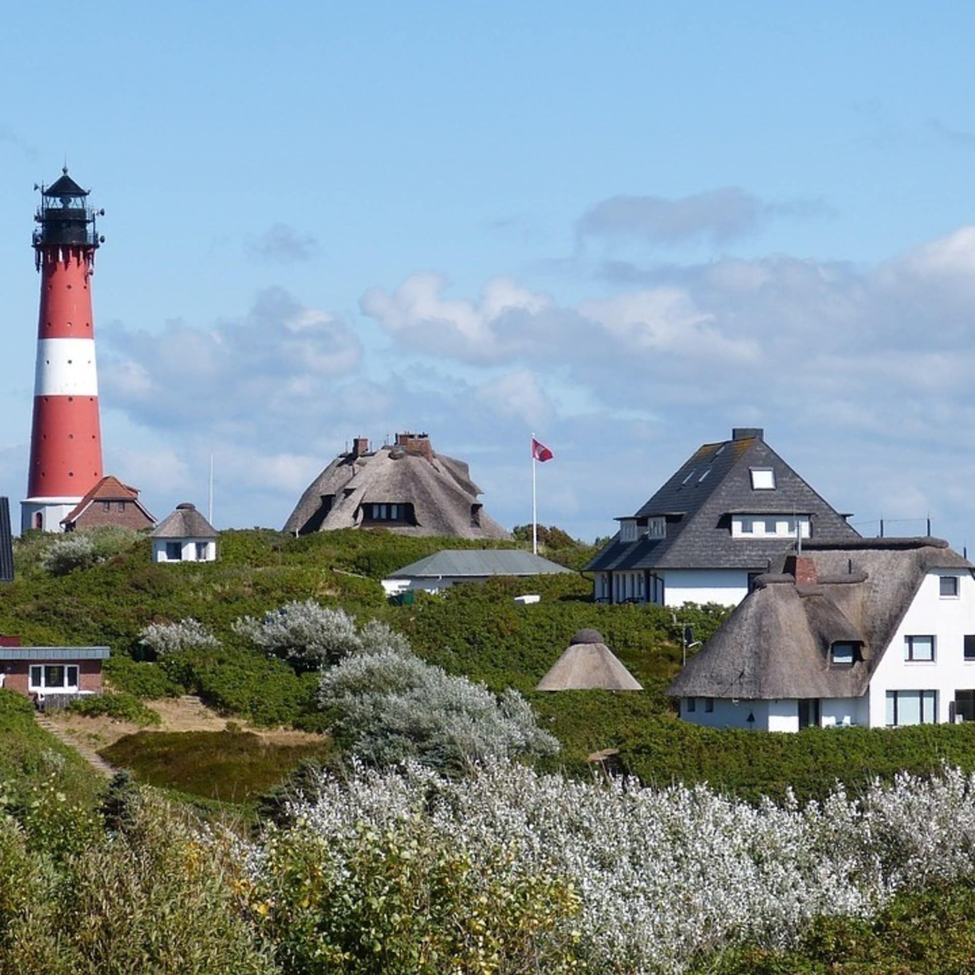 Villen auf der Insel Sylt mit Leuchtturm im Hintergrund
