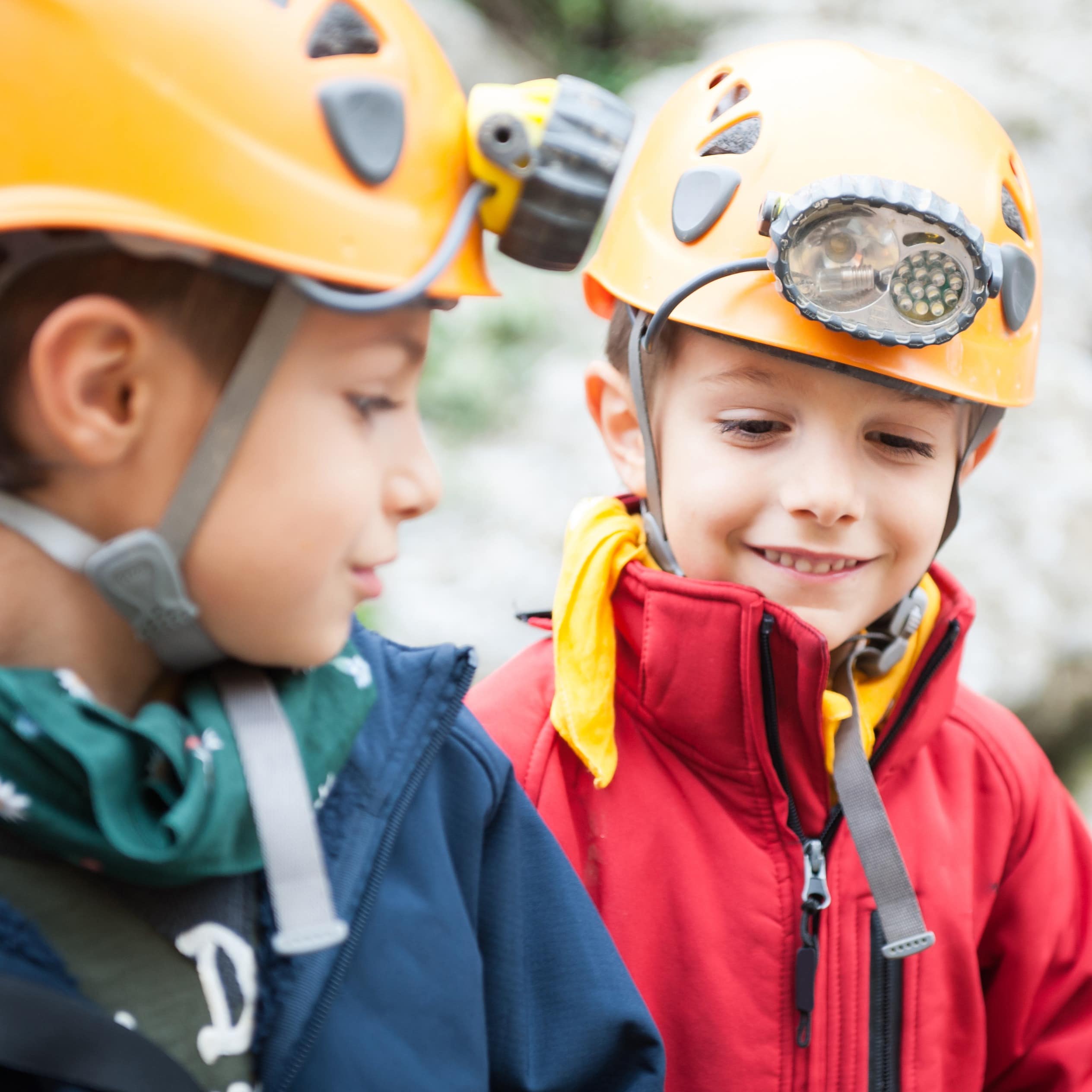 2 Jungen mit gelben Helmen mit Stirnleuchten. 