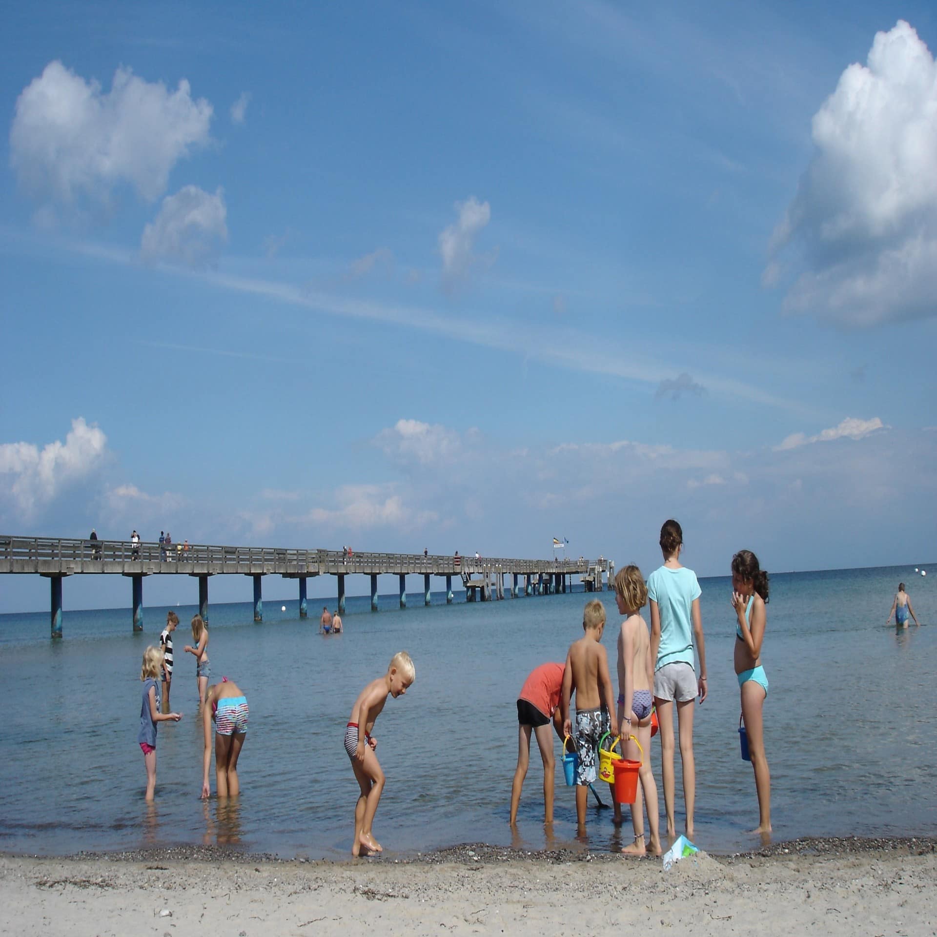 Kinder spielen im Wasser neben der Seebrücke