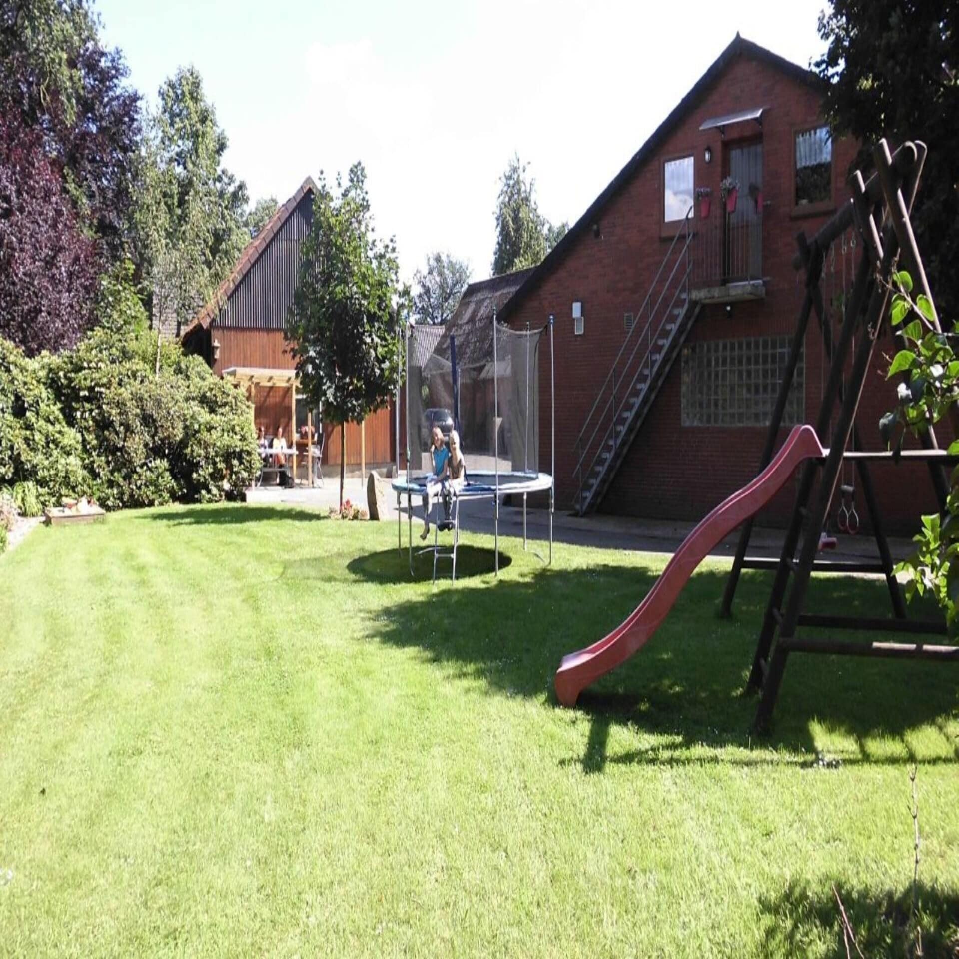 Kinder auf einem Trampolin in einem Garten mit Spielplatz
