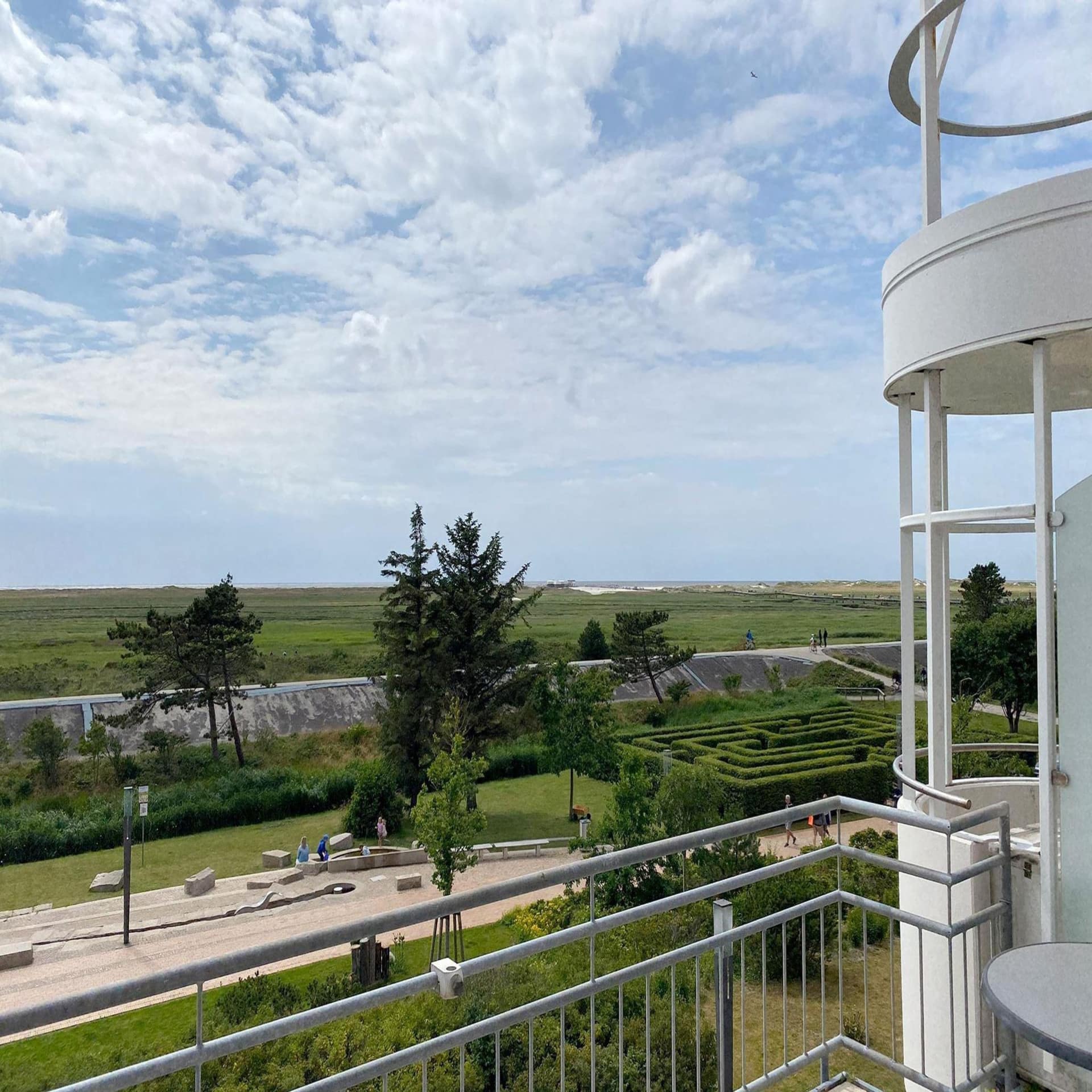 Balkon einer Wohnung in St. Peter Ording mit Blick auf eine Freizeitanlage, den Deich und das Meer