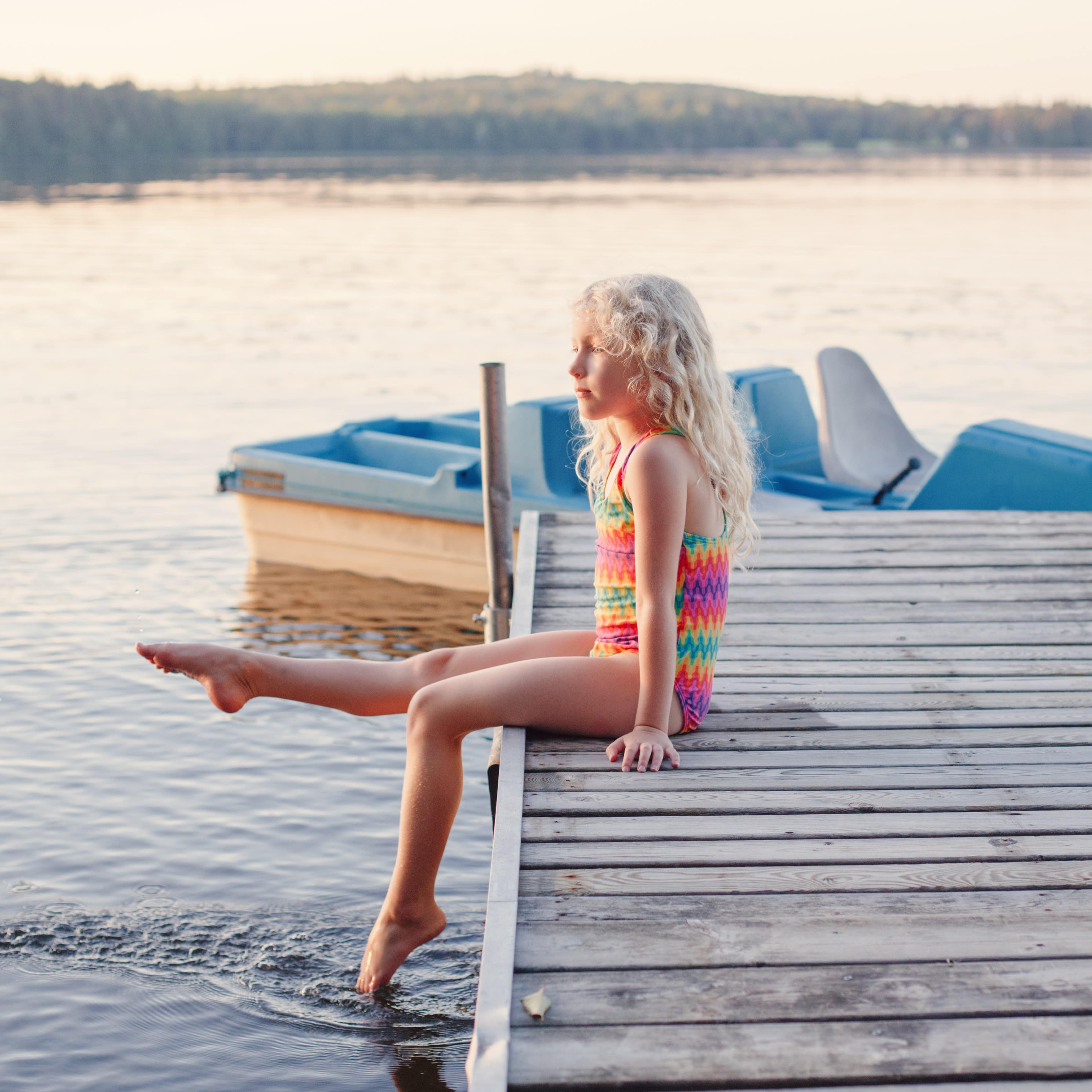 Ein Mädchen in Badeanzug auf einem Steg an einem See.