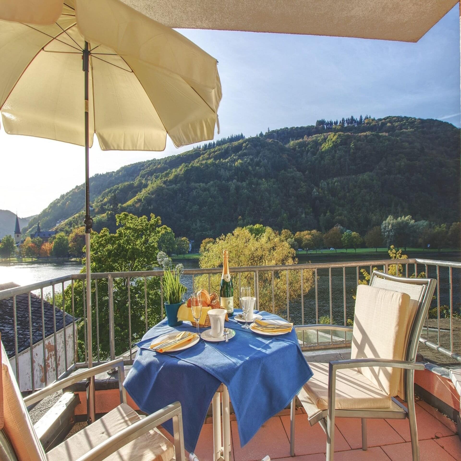 Balkon mit gedecktem Frühstückstisch für 2 Personen und Blick auf die Mosel. Die Sonne scheint.