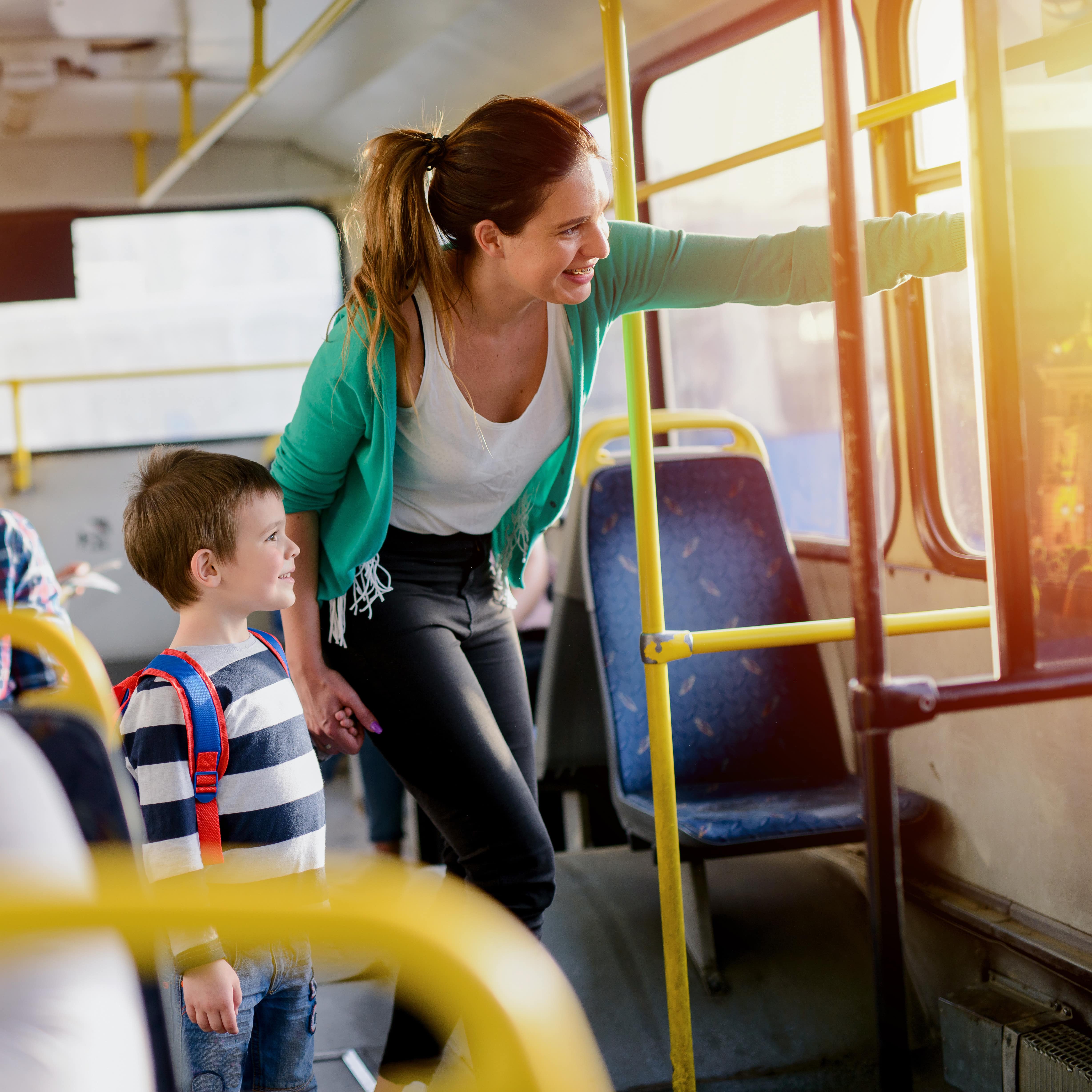 Mutter und Sohn im Bus. Die Mutter zeigt auf etwas.