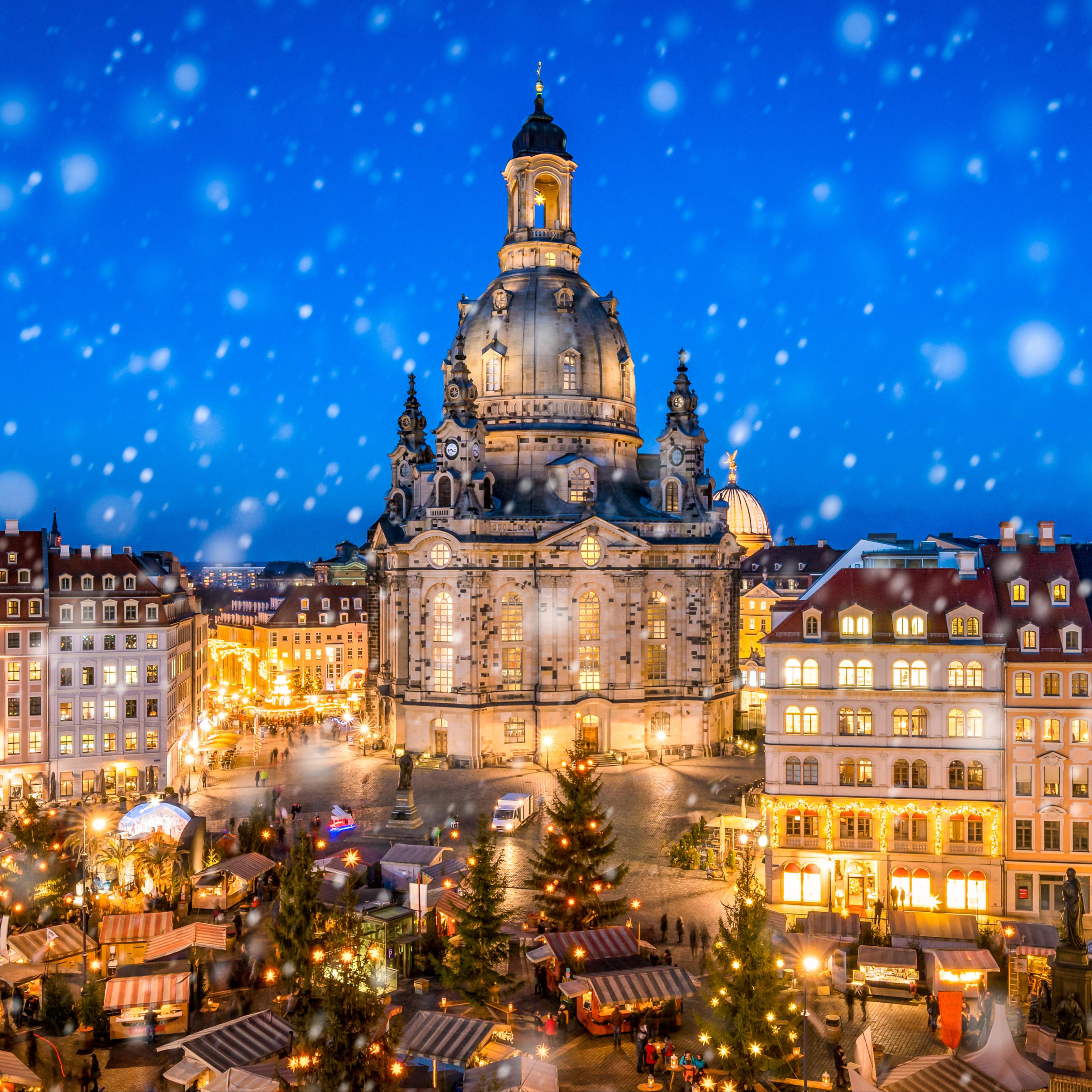 Blick von oben auf den Weihnachtsmarkt in der Dämmerung, es schneit.