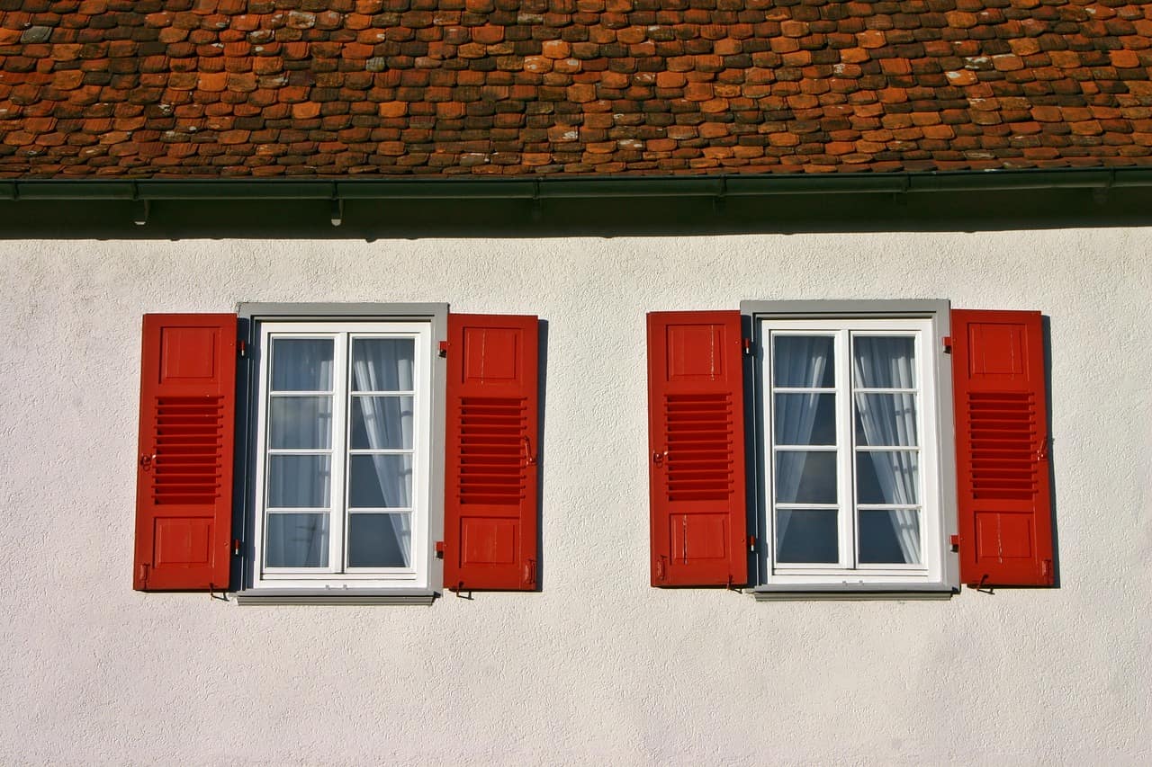 Nahaufnahme einer Hauswand mit roten Fensterläden